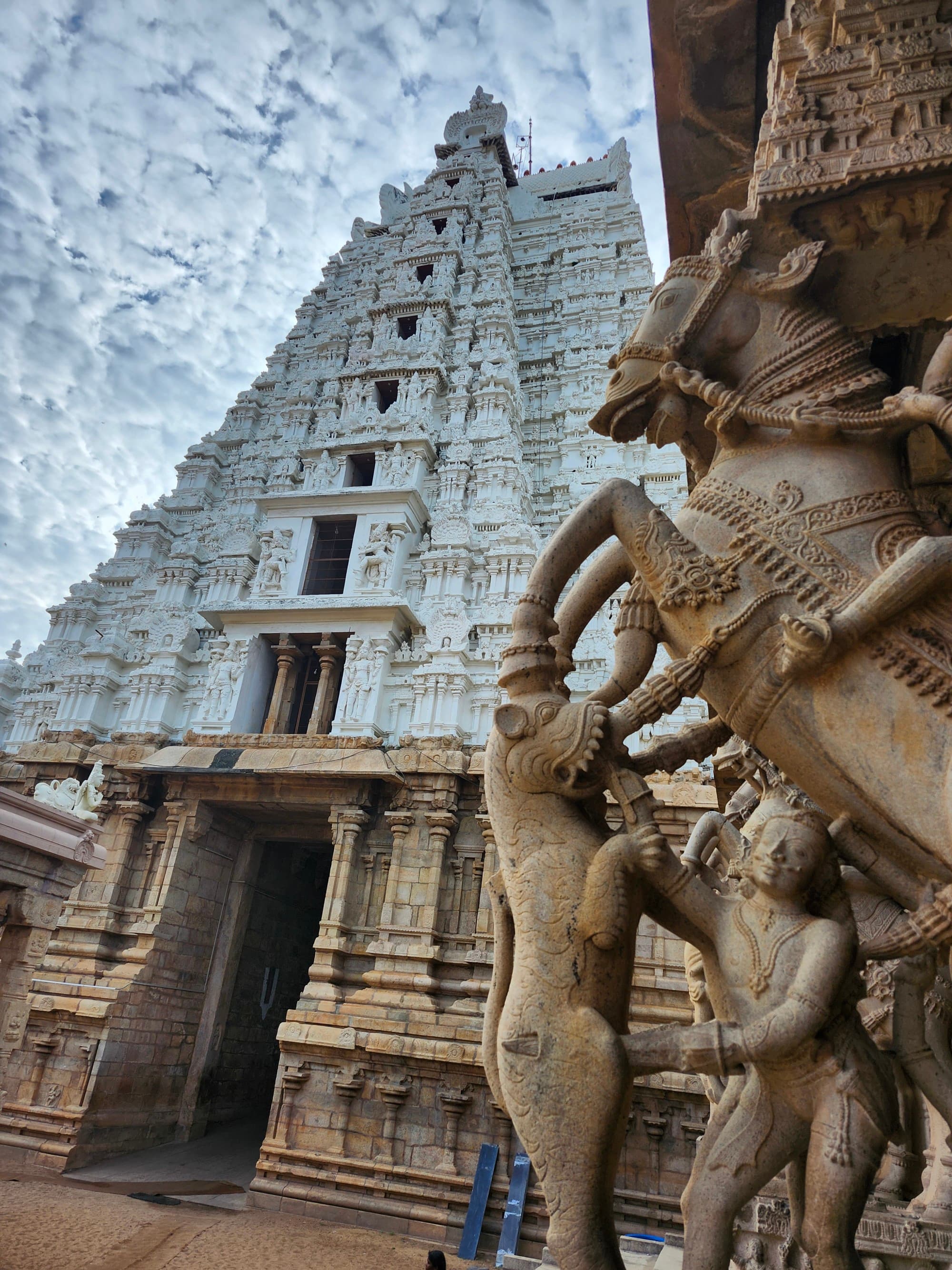 An intricately carved stone temple with sculptures of figures and animals stands under a cloudy sky.