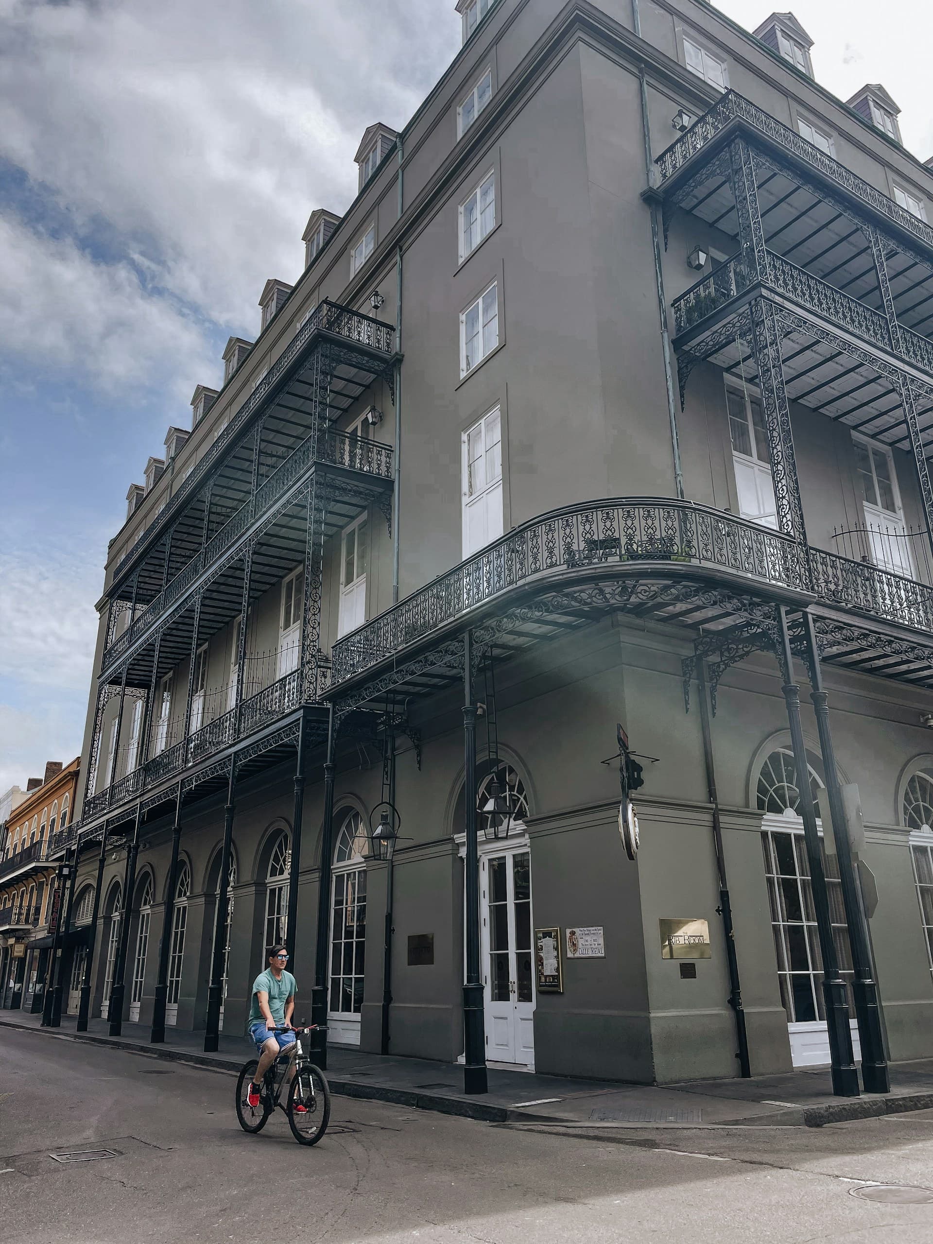 A person on a bicycle passing by Bienville House Hotel, a French-Quarter manor house,