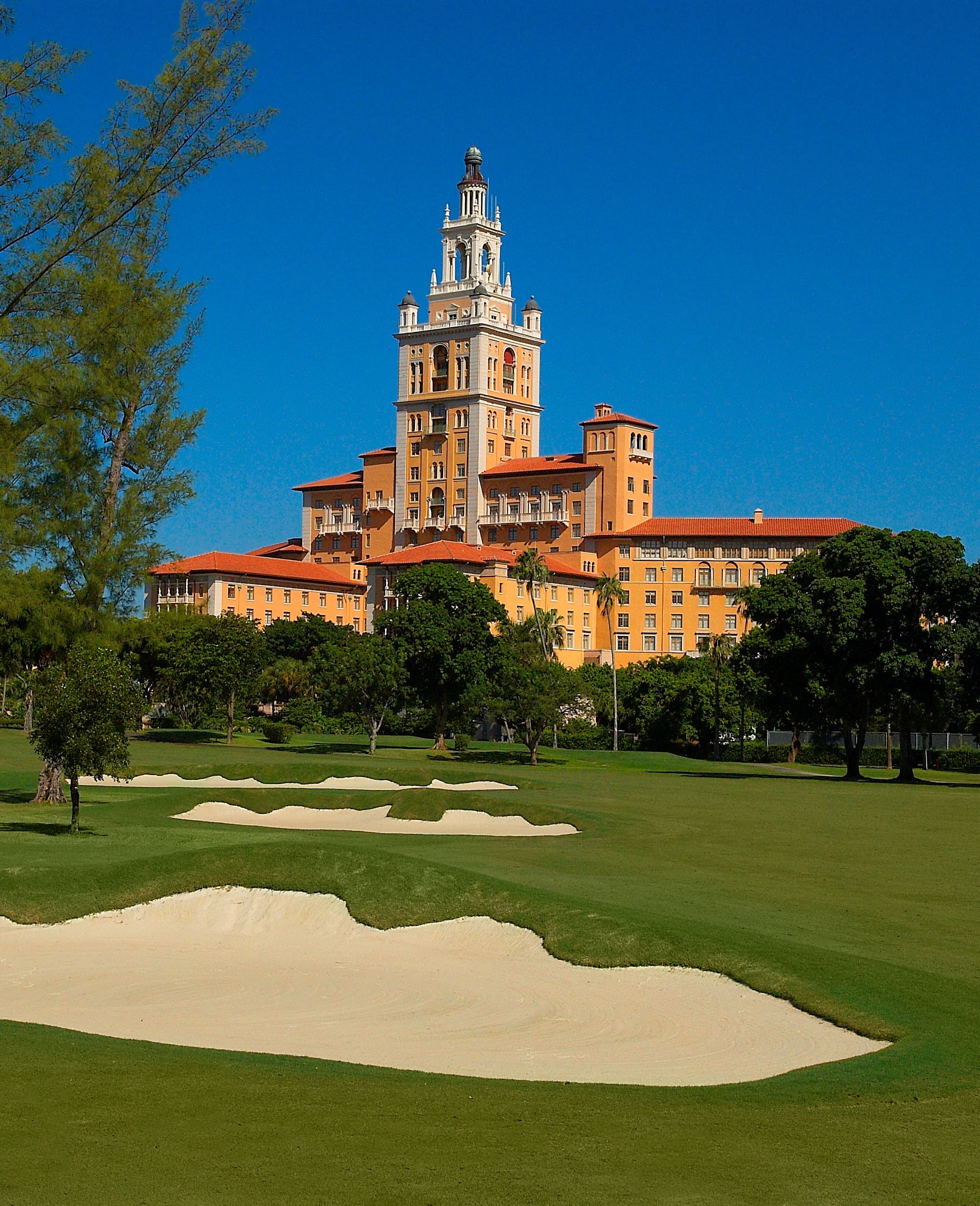 A large orange building behind a golf course during the daytime