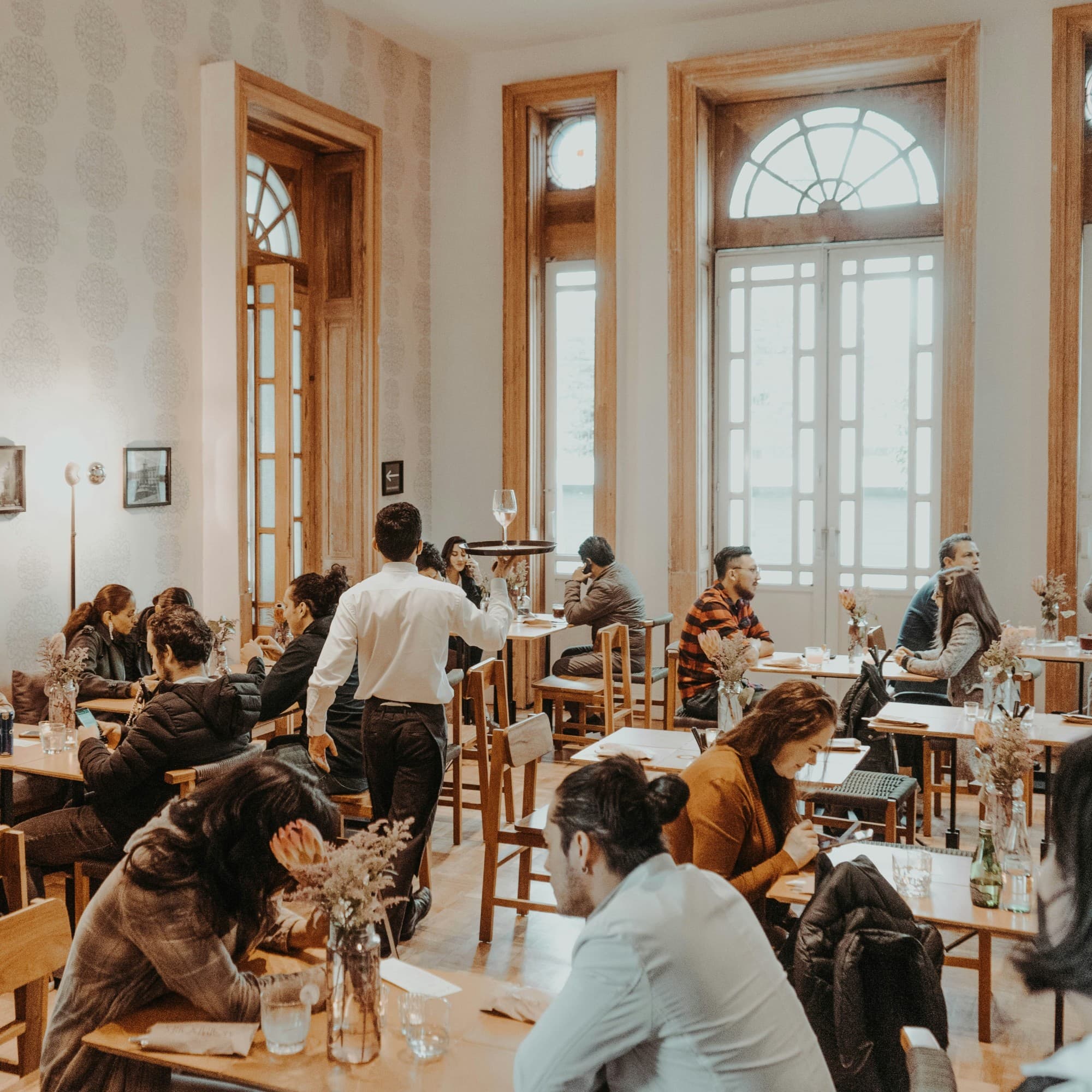 A bustling indoor café with patrons enjoying conversations and individual activities.