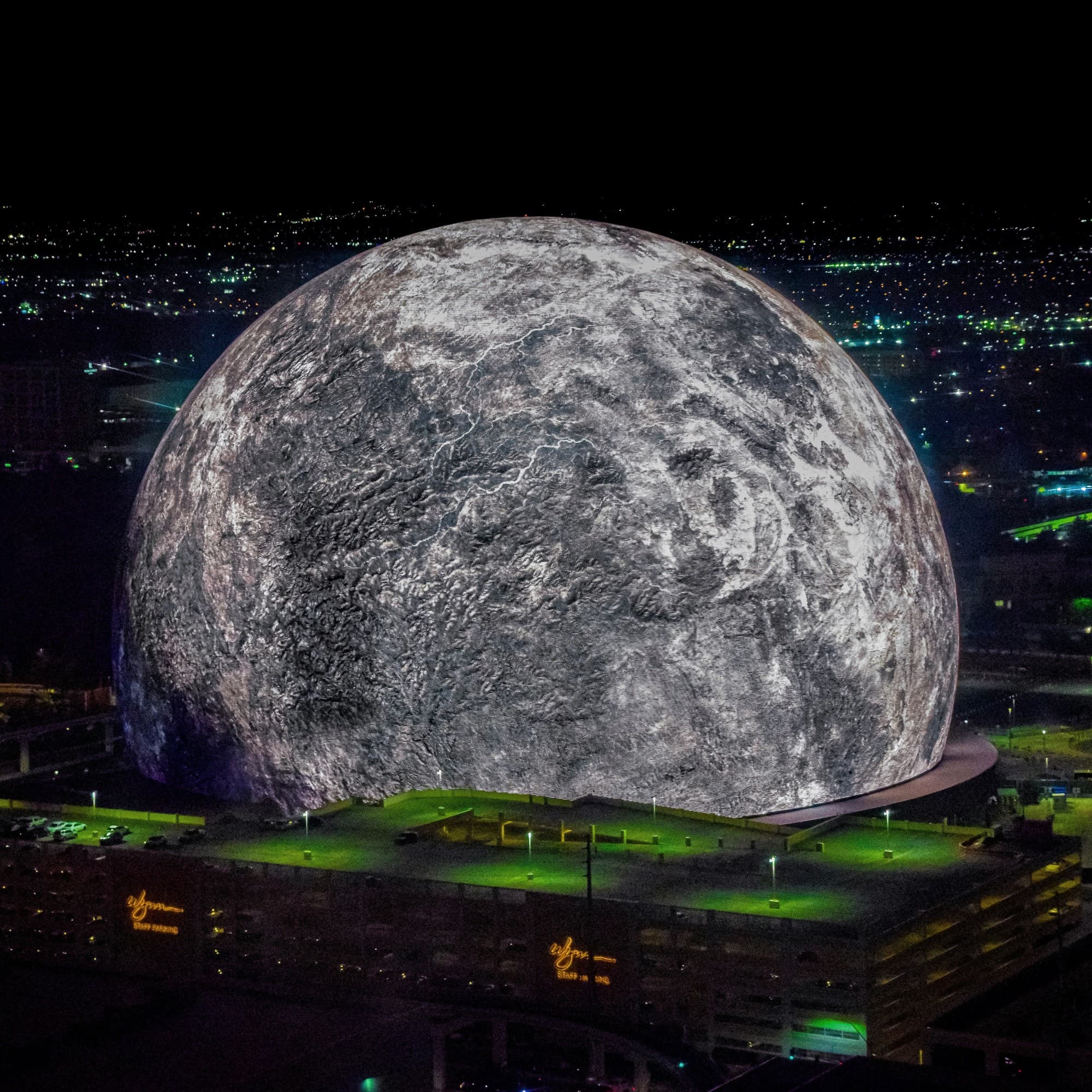 A large moon sphere over city at night.