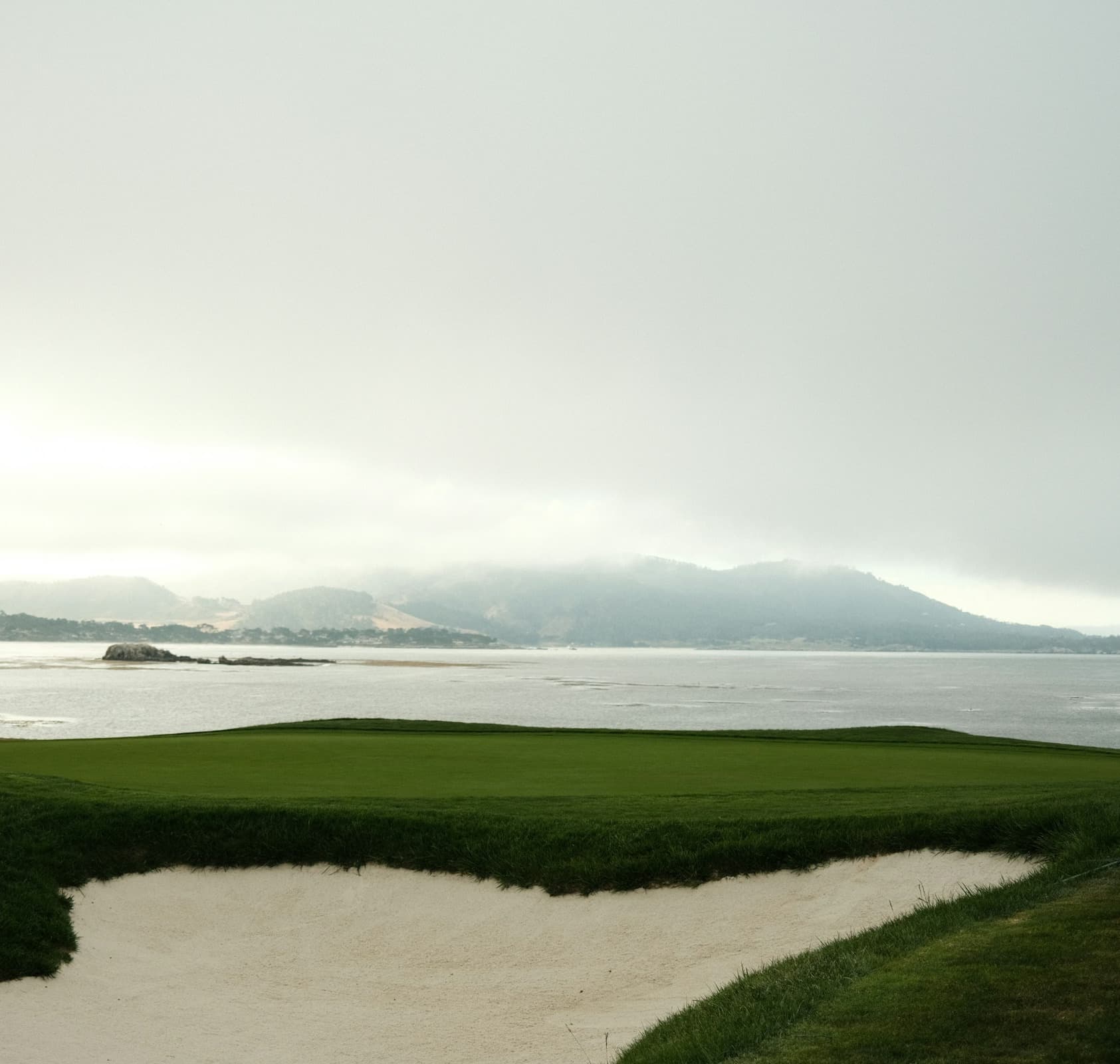 A golf course next to a body of water during an overcast day