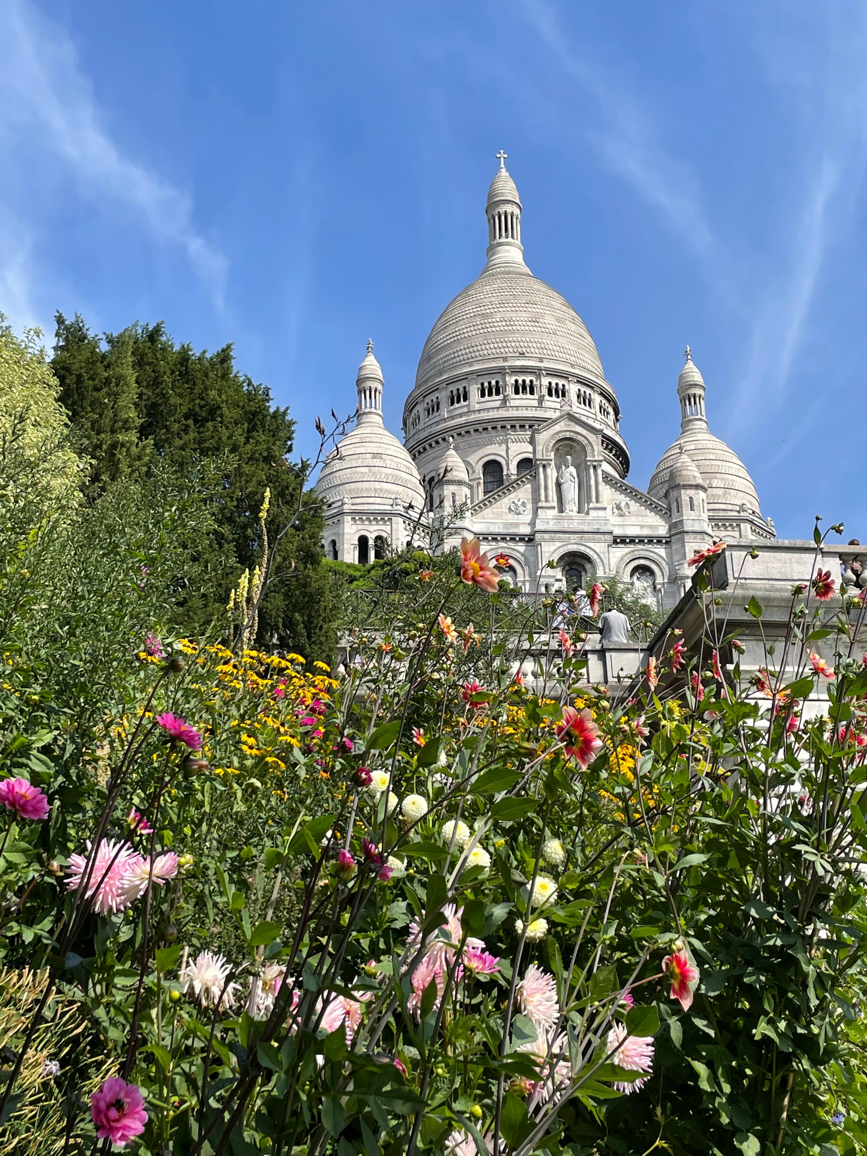 The iconic white-domed Sacré-Cœur Basilica atop Montmarte with flowers in the foreground.