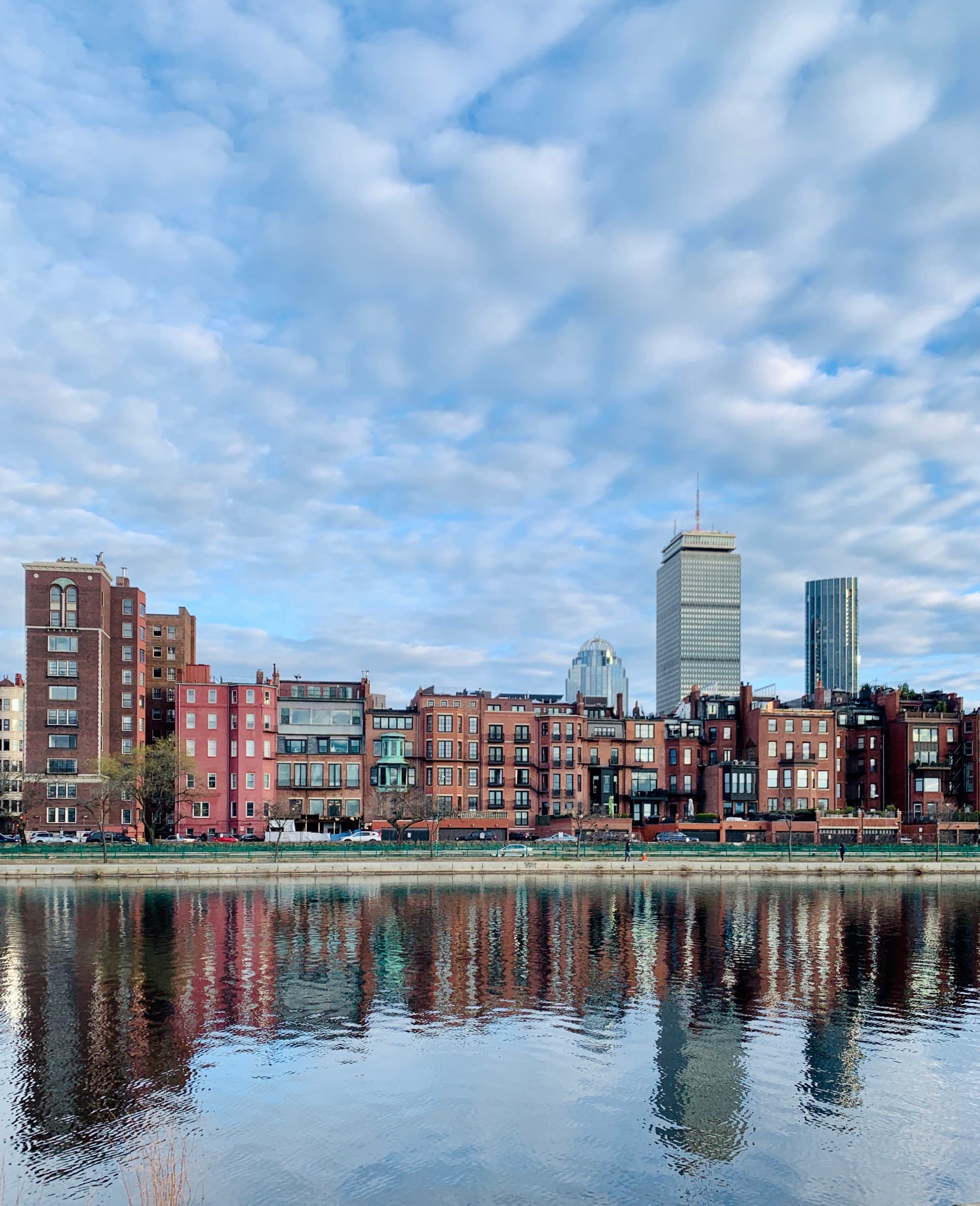 A view of the city from over the water with a cloudy sky overhead.