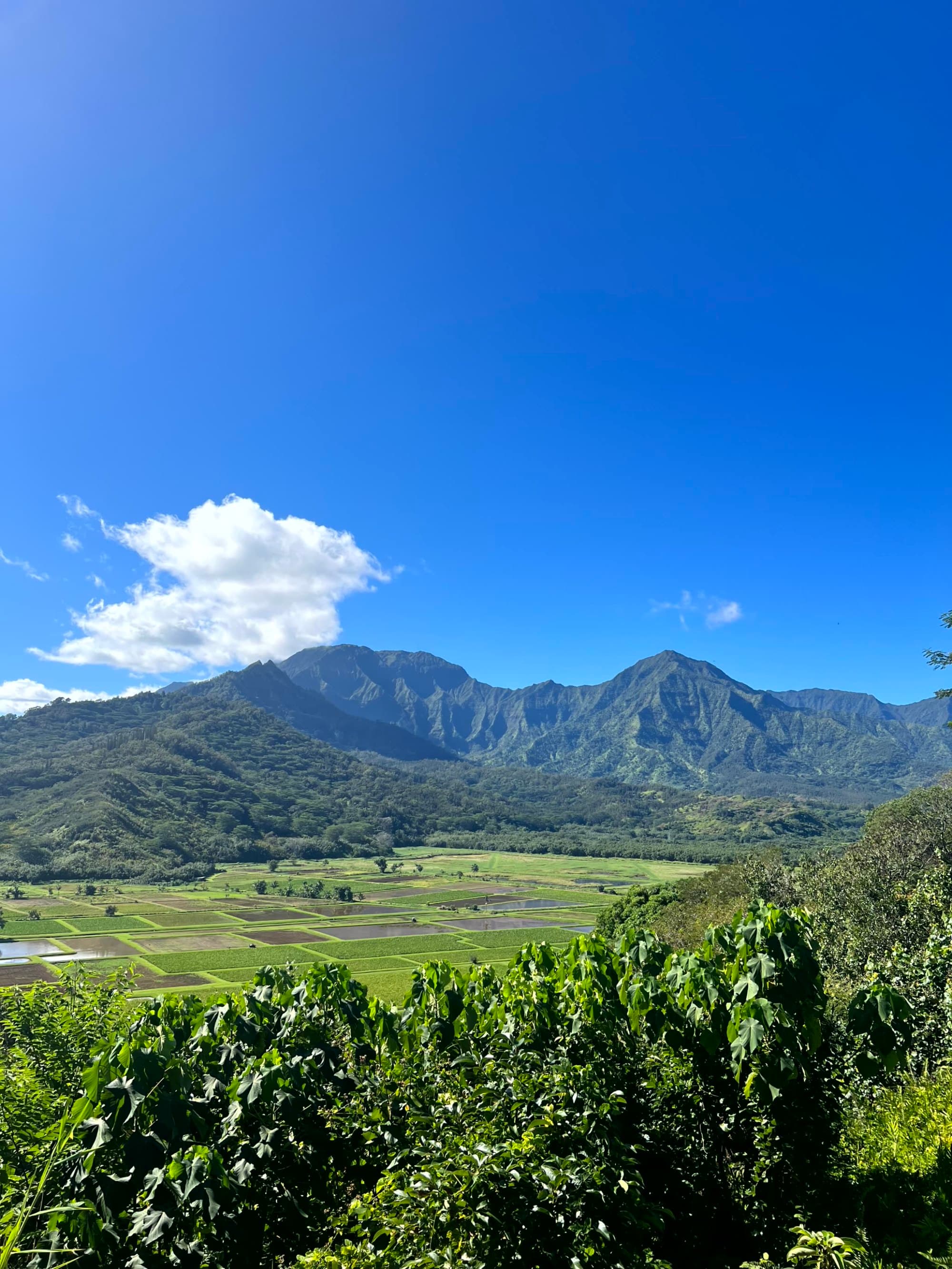 A mountain with a unique heart-shaped opening near its peak stands under a blue sky with clouds.