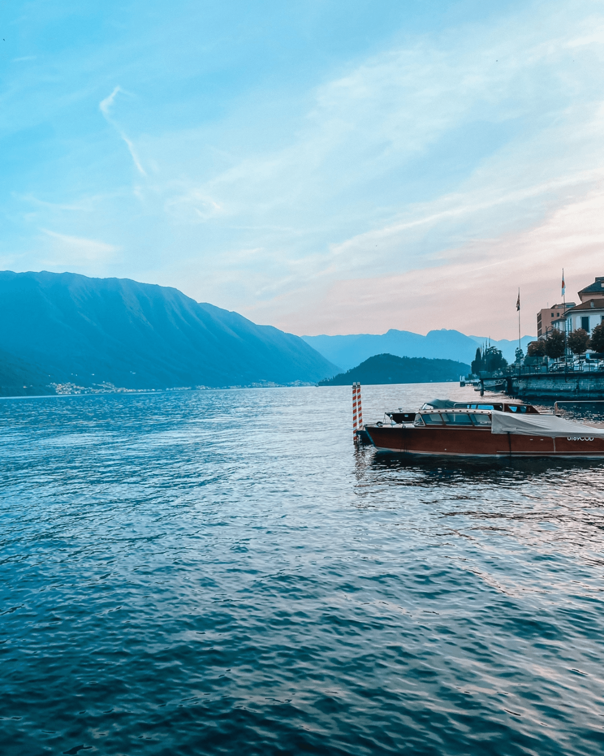 View of boats on a lake during the daytime with a mountain range in the distance