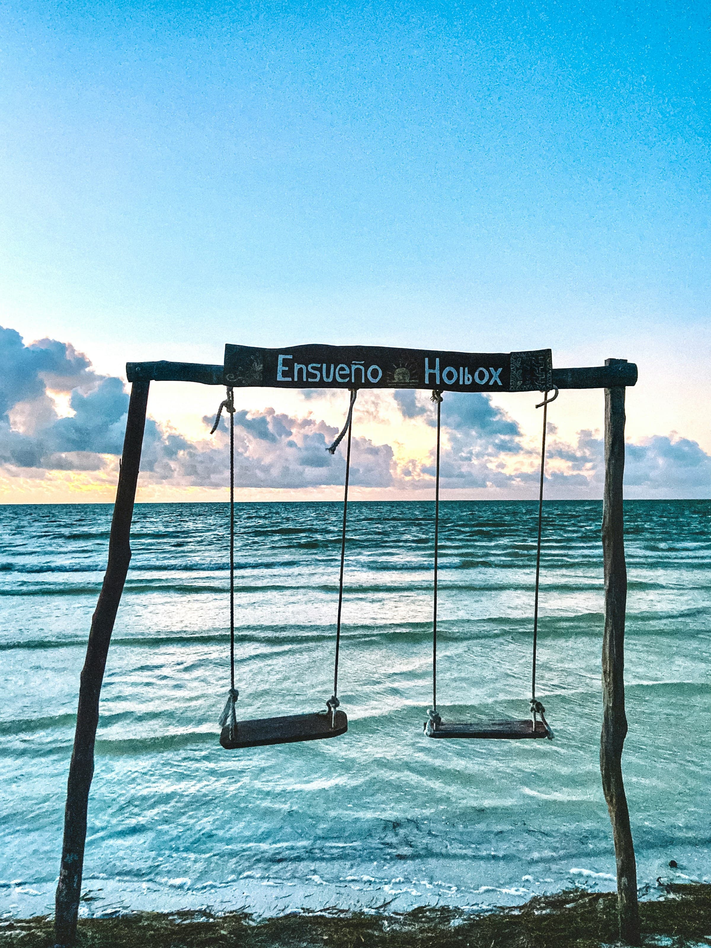 A set of swings next to a beach during the daytime