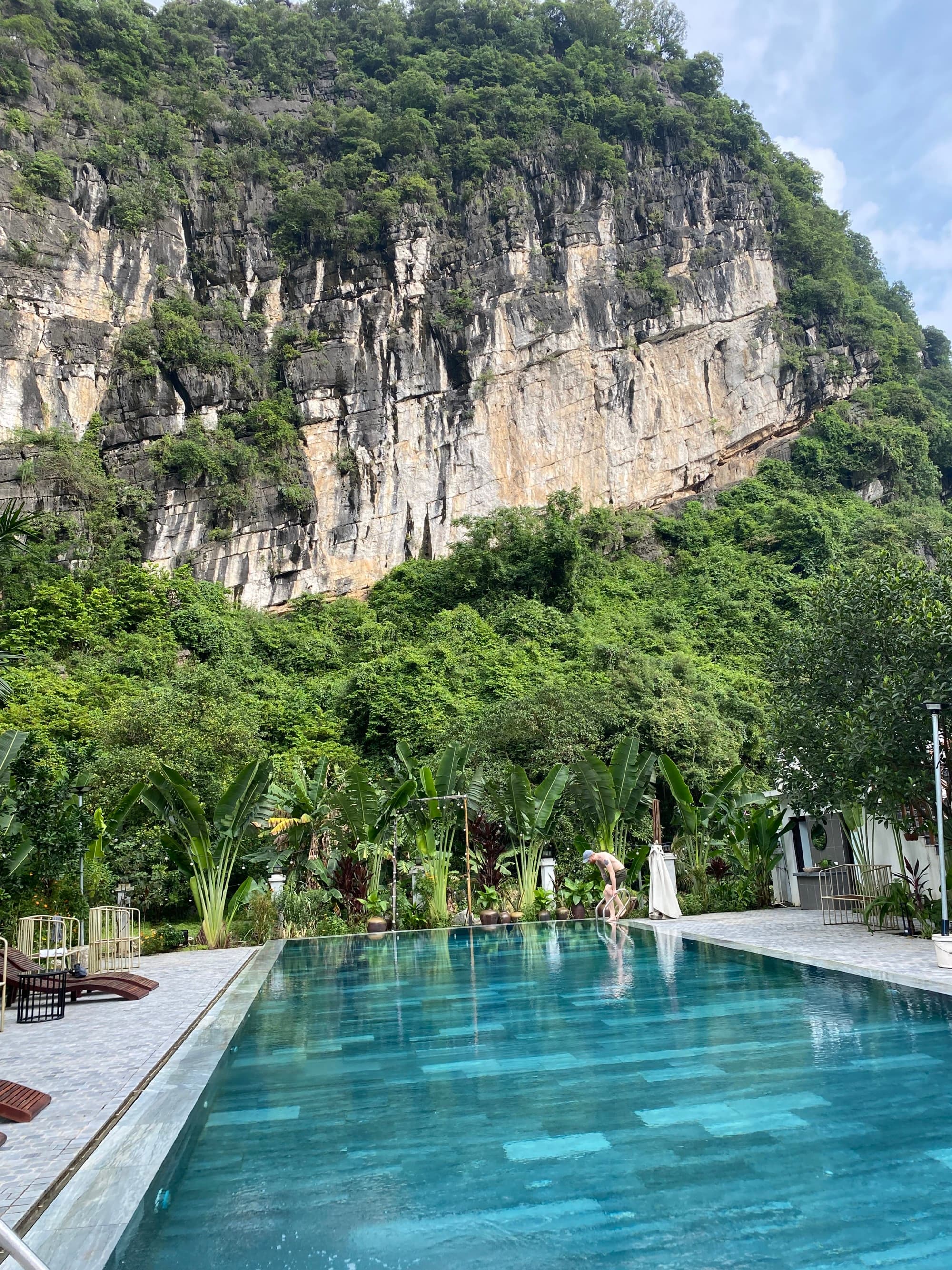 An outdoor swimming pool at the bottom of a tree-covered mountainside