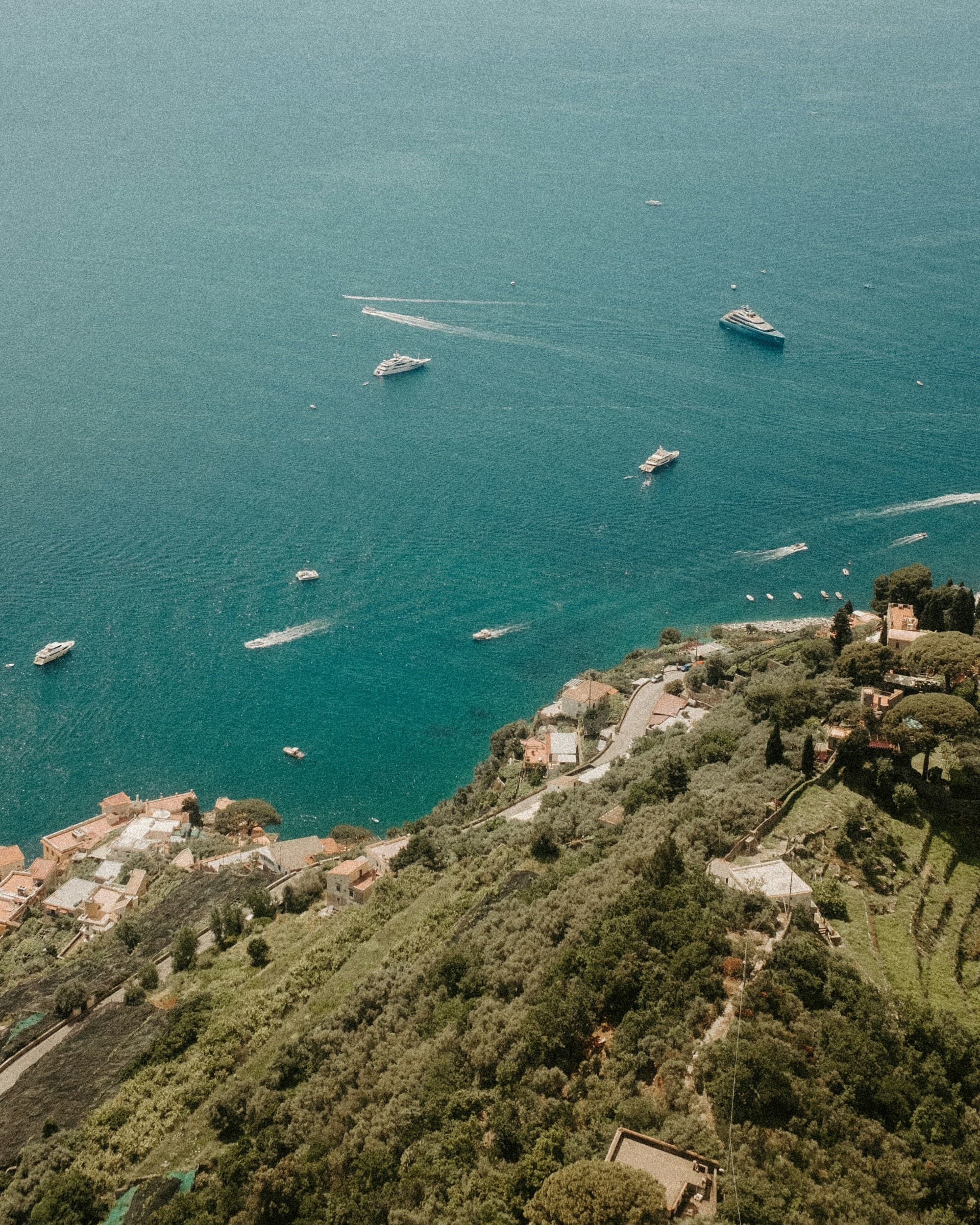 Boats in a body of water next to a cliffside during the daytime