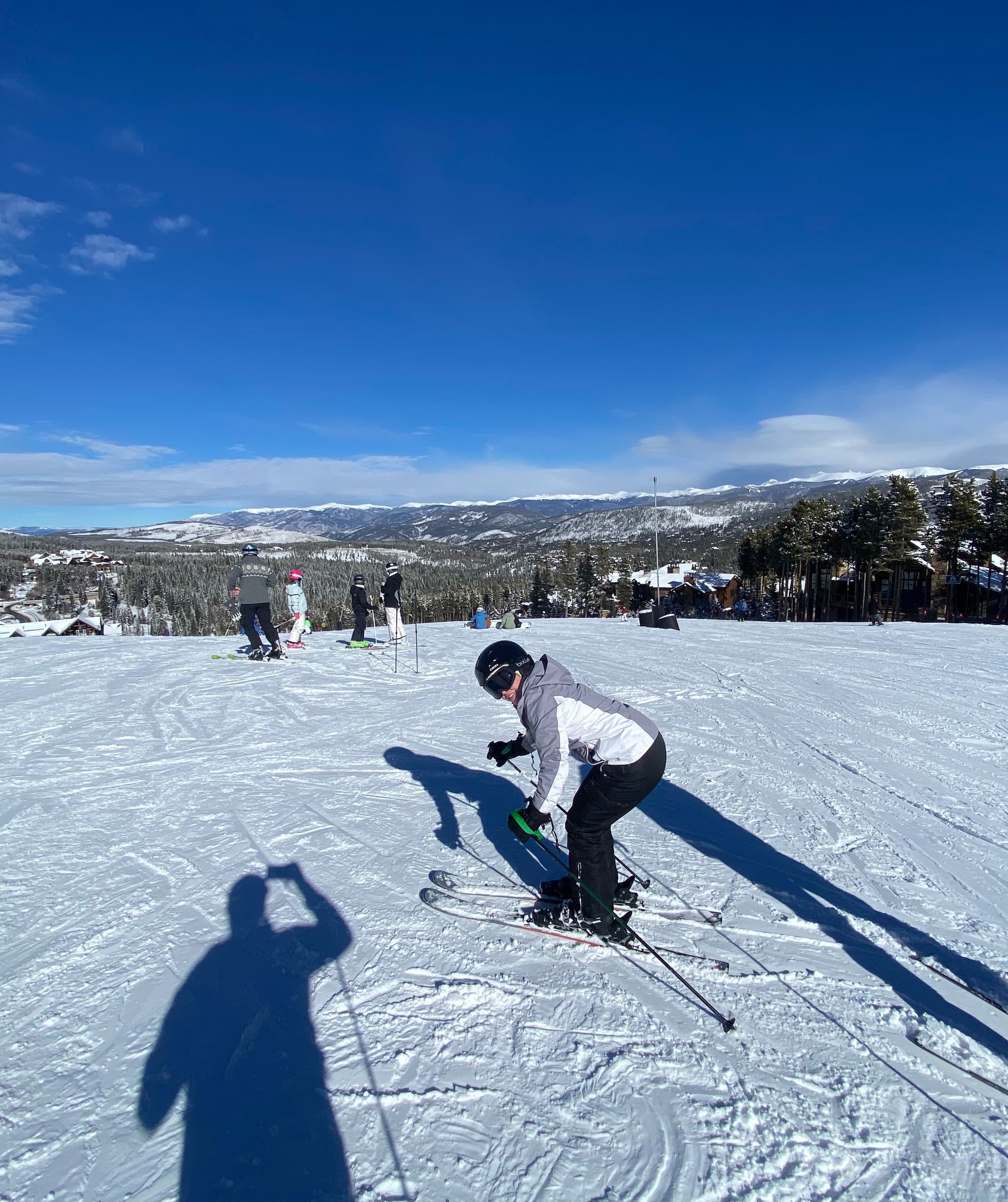 A woman leans forward on skies on a wide field of snow.