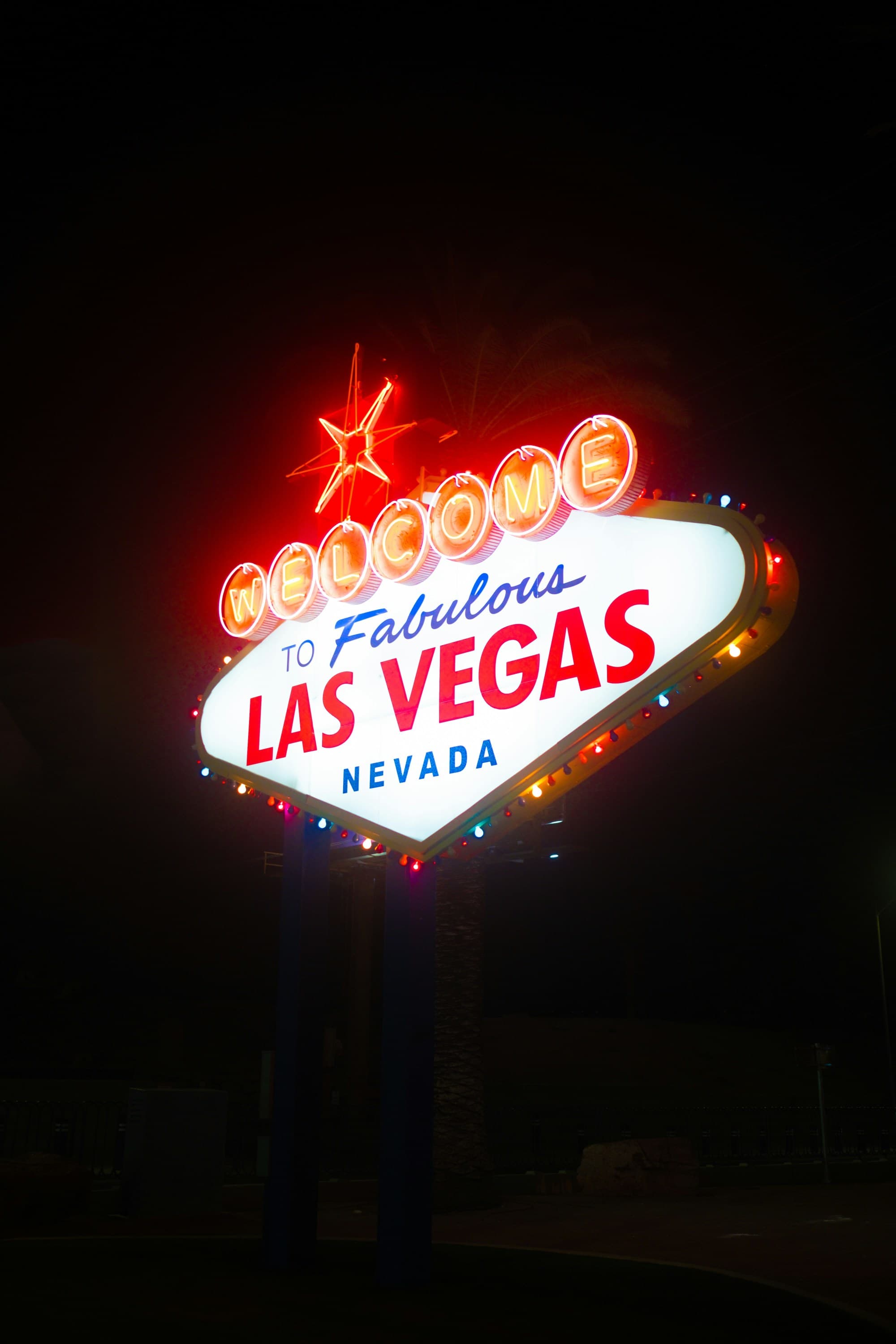 The image shows the iconic “Welcome to Fabulous Las Vegas Nevada” sign illuminated at night.