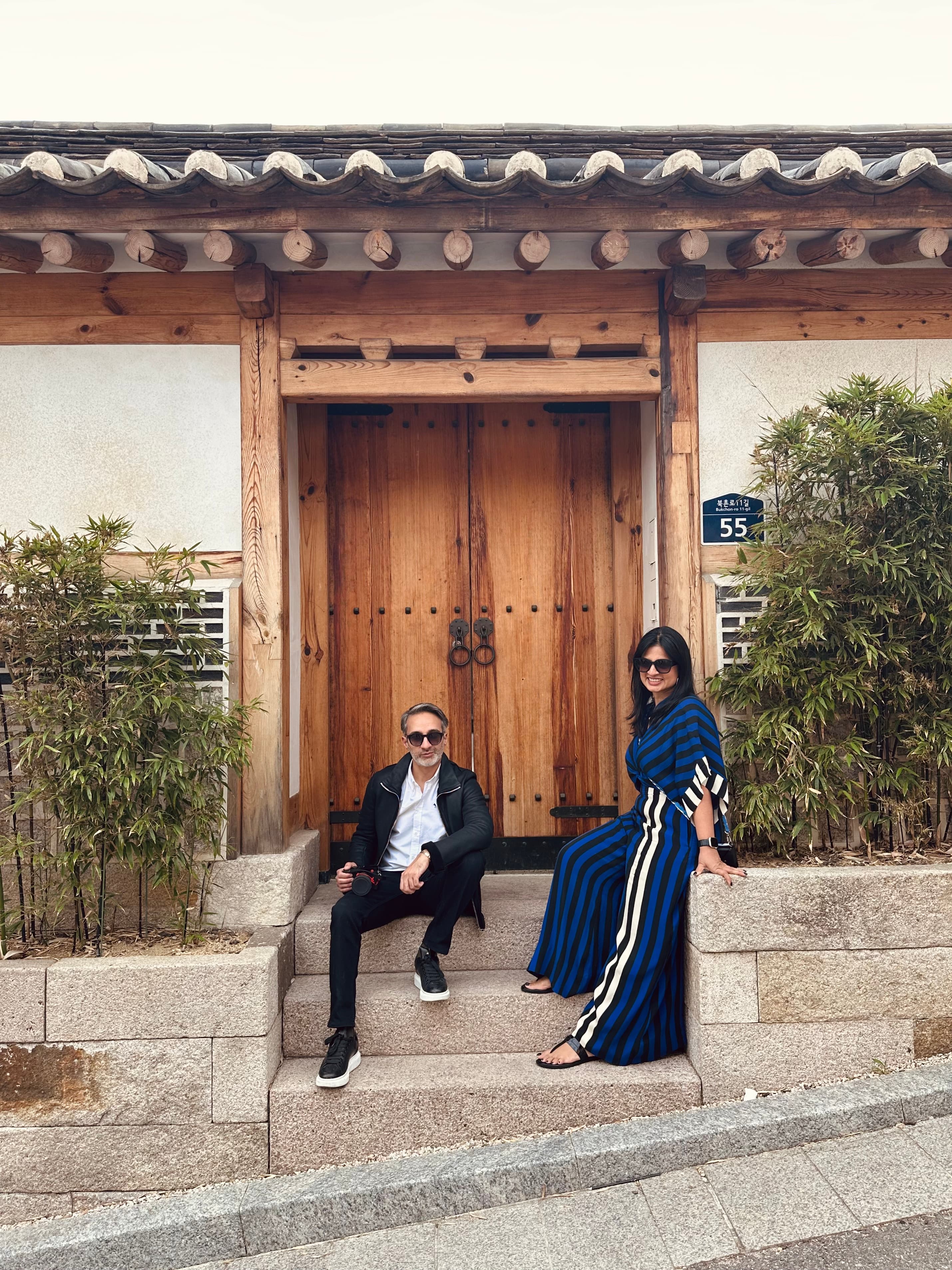 Two people posing for a photo in front of a building