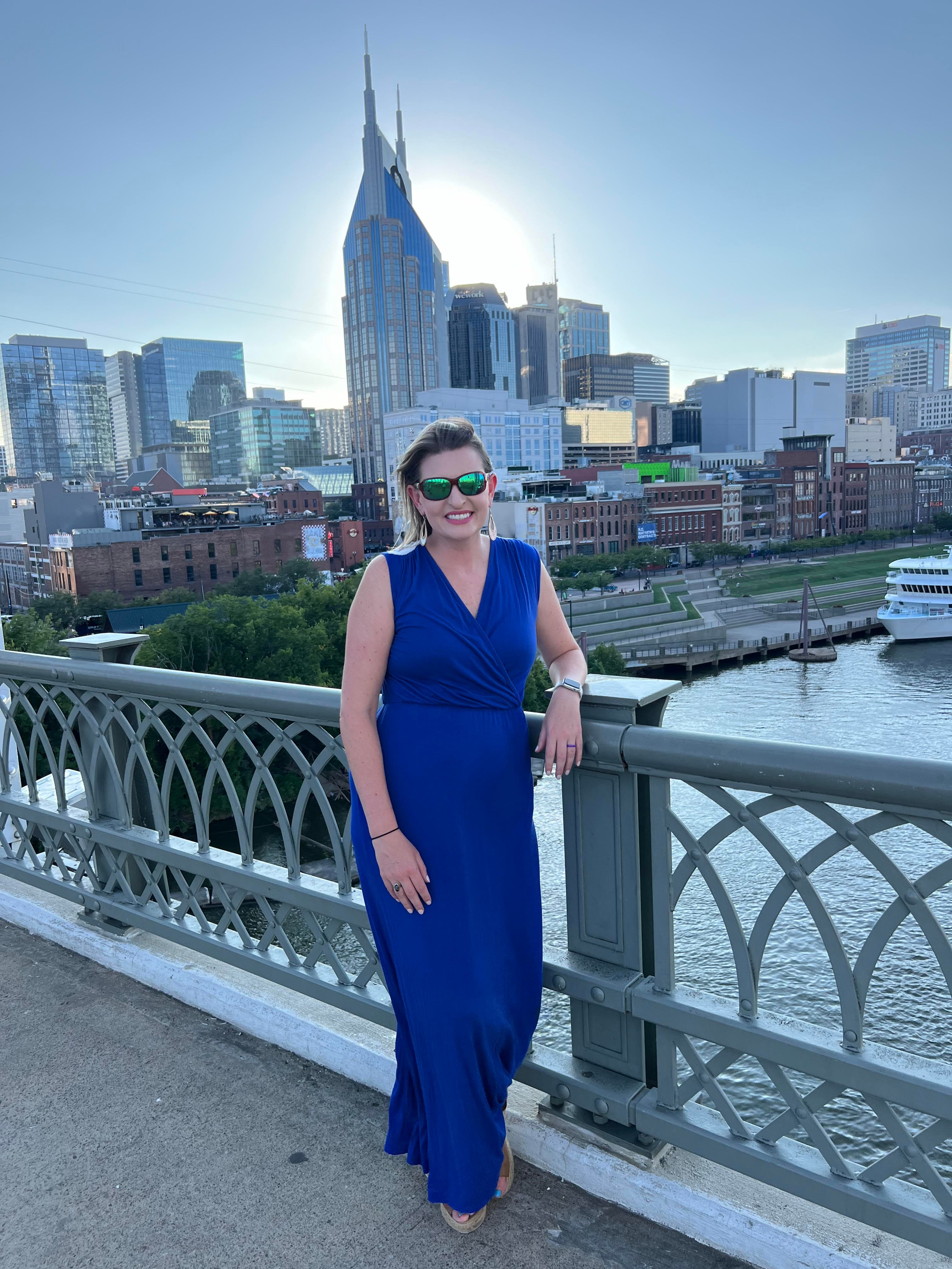 A person standing on a bridge posing for a photograph in front of a city skyline