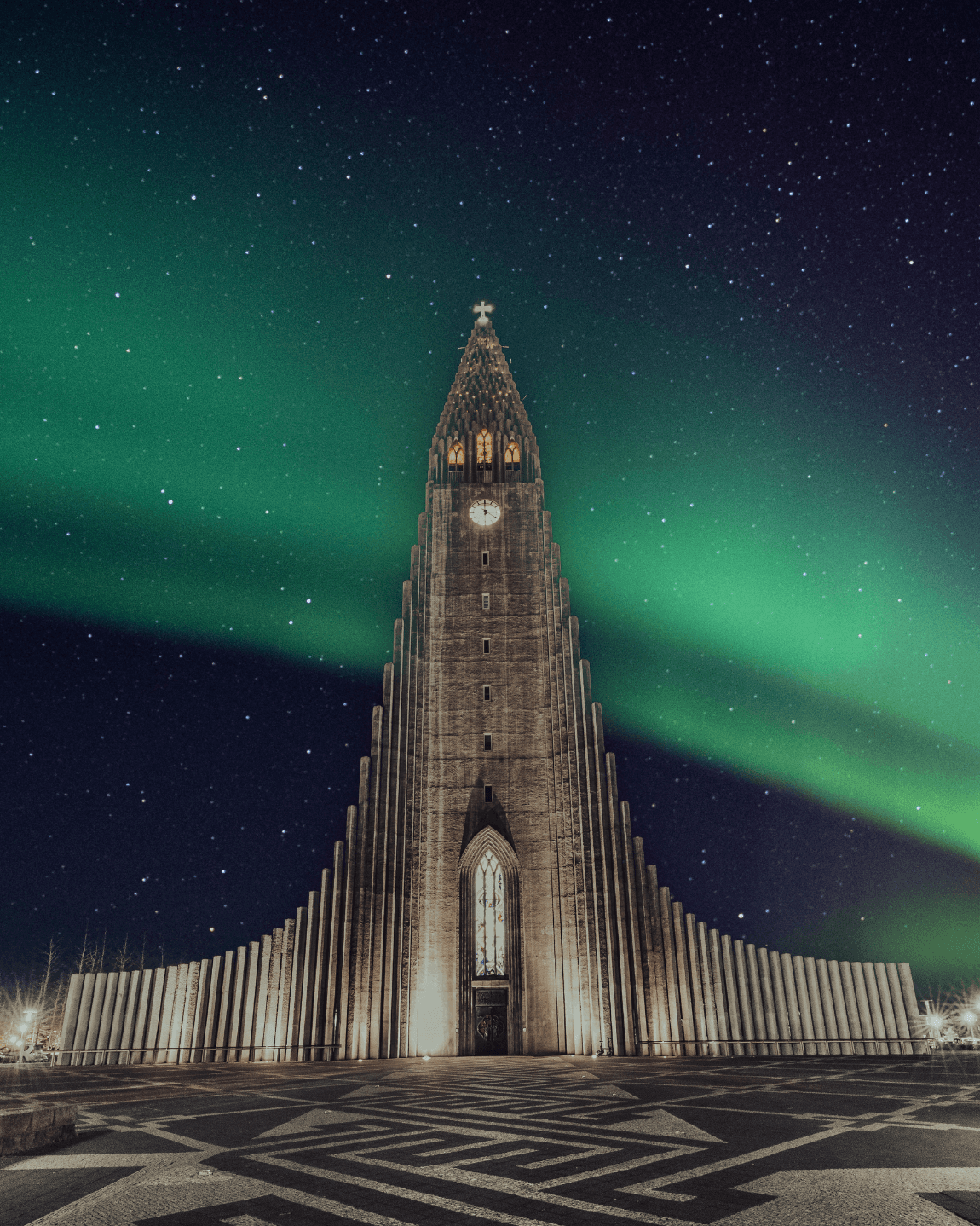 A large, cathedral-like building in front of bright green lights in the sky at night