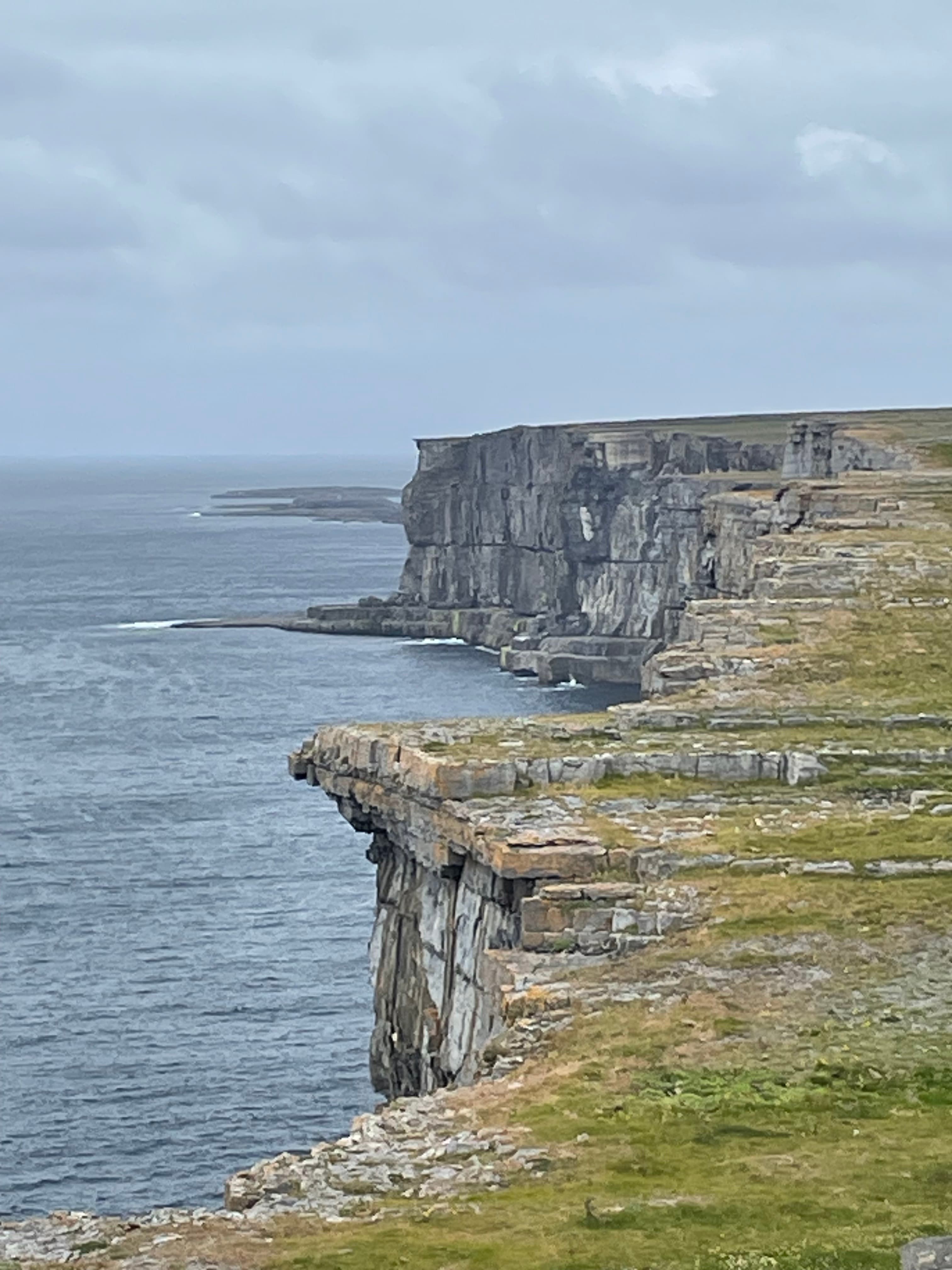 Cliffs edge next to a body of water during a cloudy day