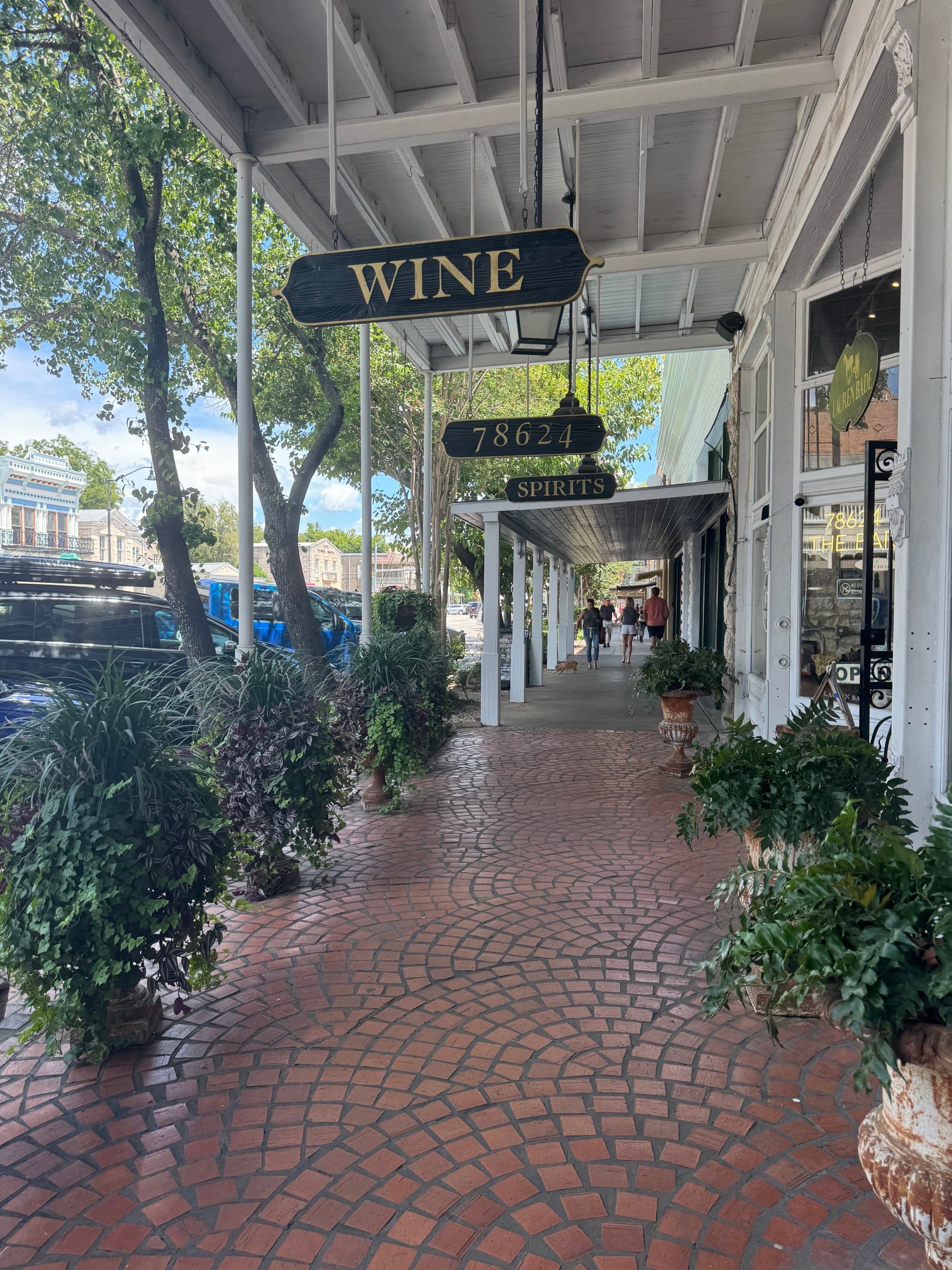 A cobblestone street with a “Wine” sign hanging from a white building.