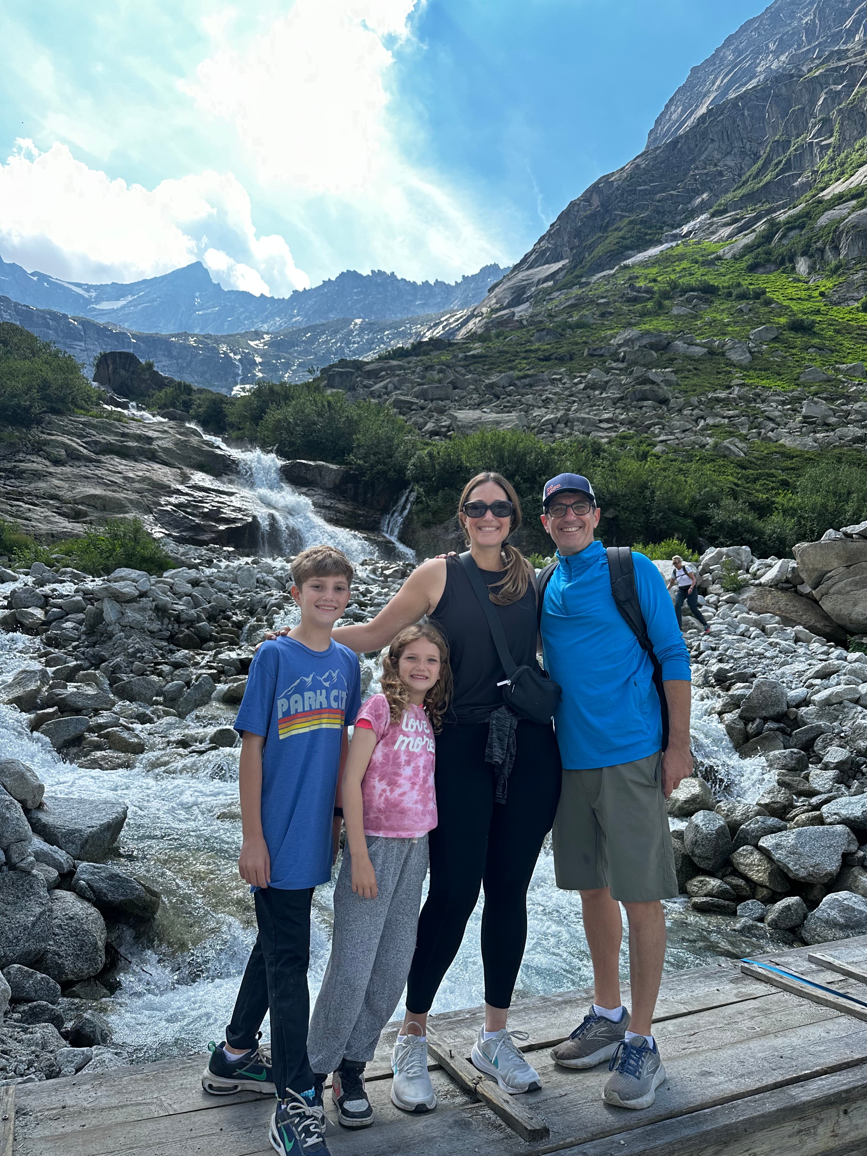 A family of four — two adults and two children — on the rocky slopes of a mountain.