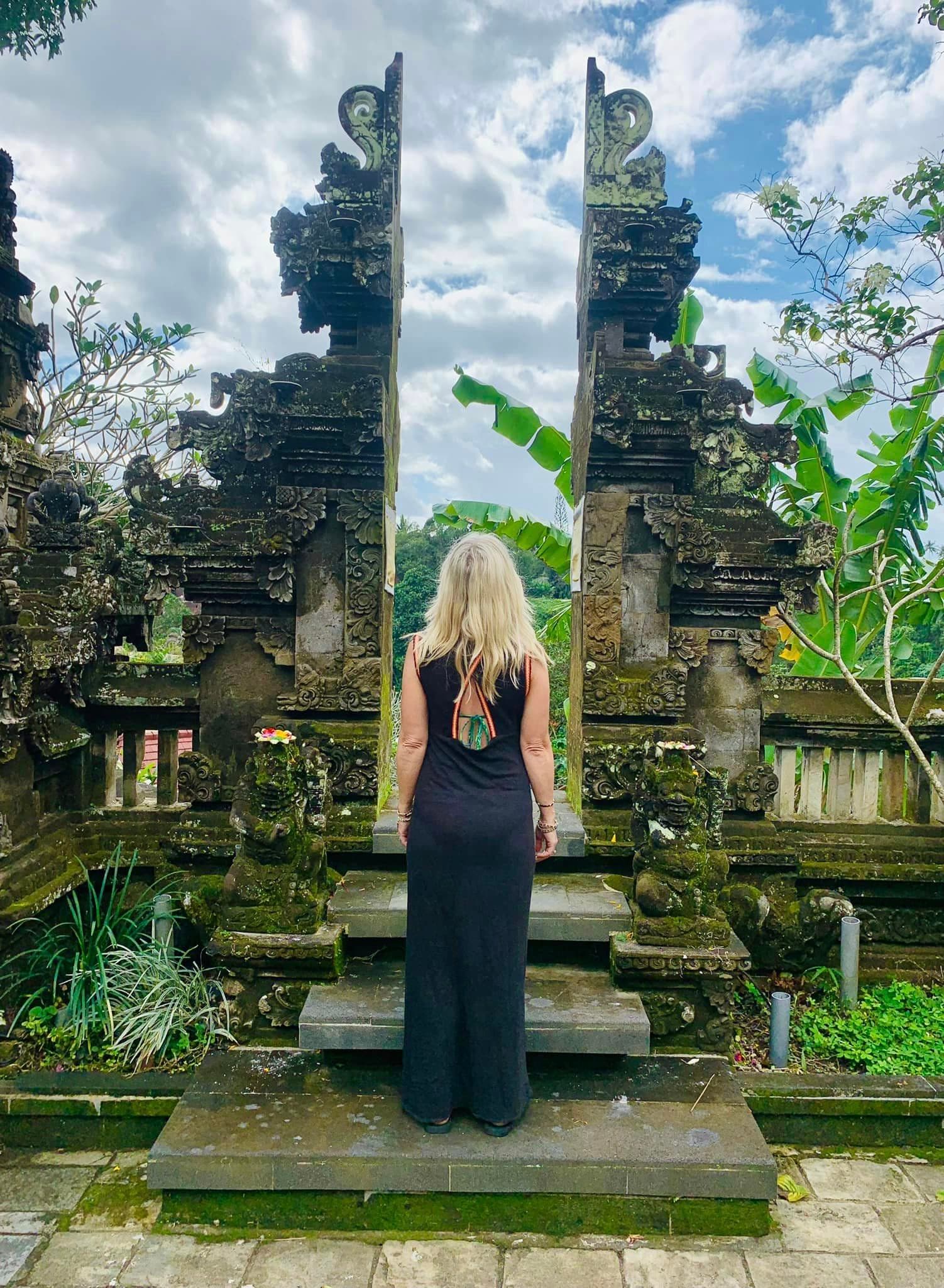 A person standing in front of two tall, stone pillars with back turned towards the camera