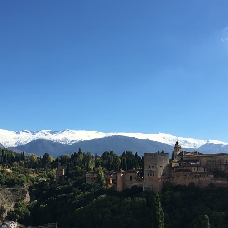 View of building, trees and snow covered mountains.