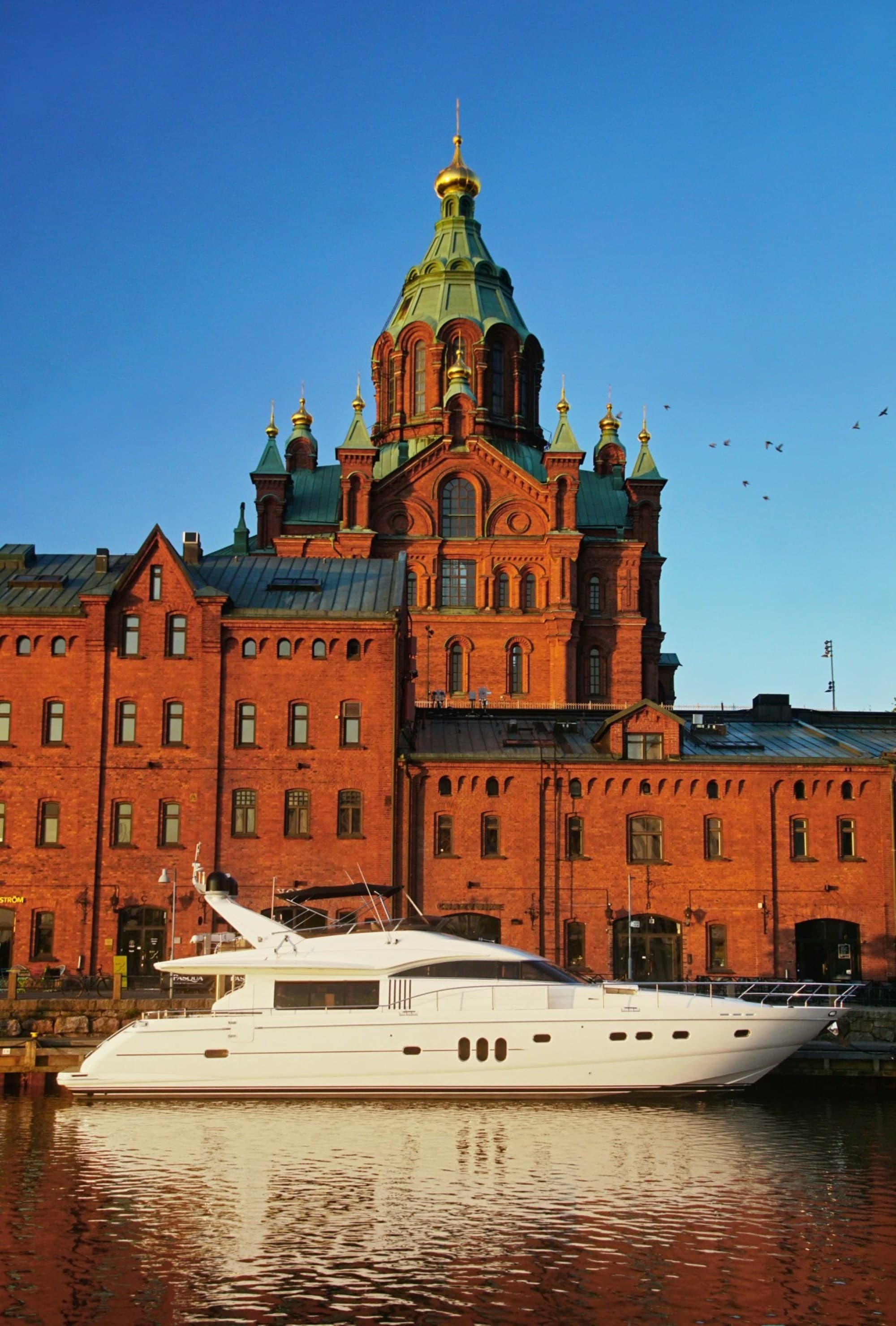 A white yacht on the waterfront of Uspenski Cathedral on a sunny day.