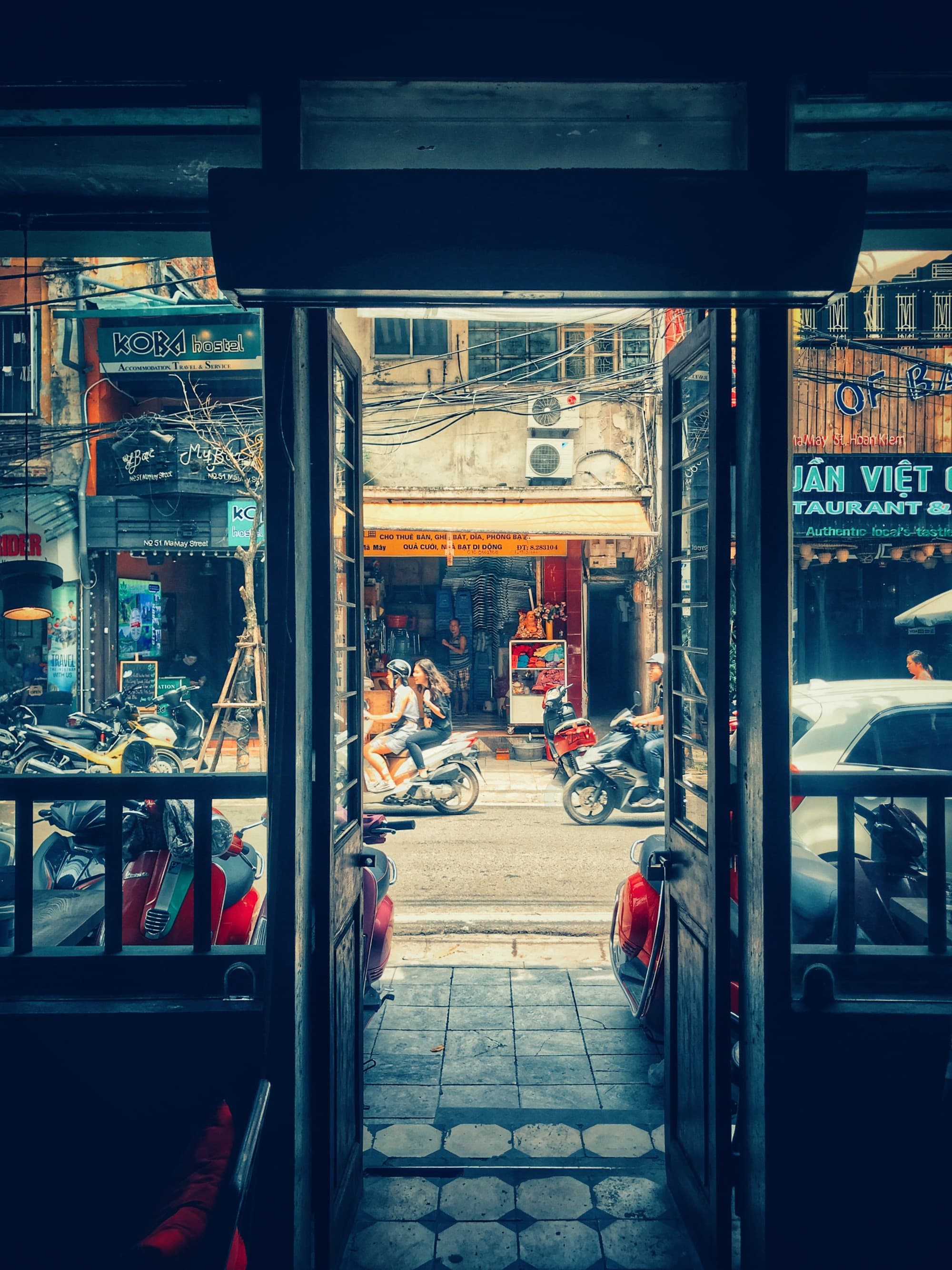 View of street with motorbikes on it from inside a shop.