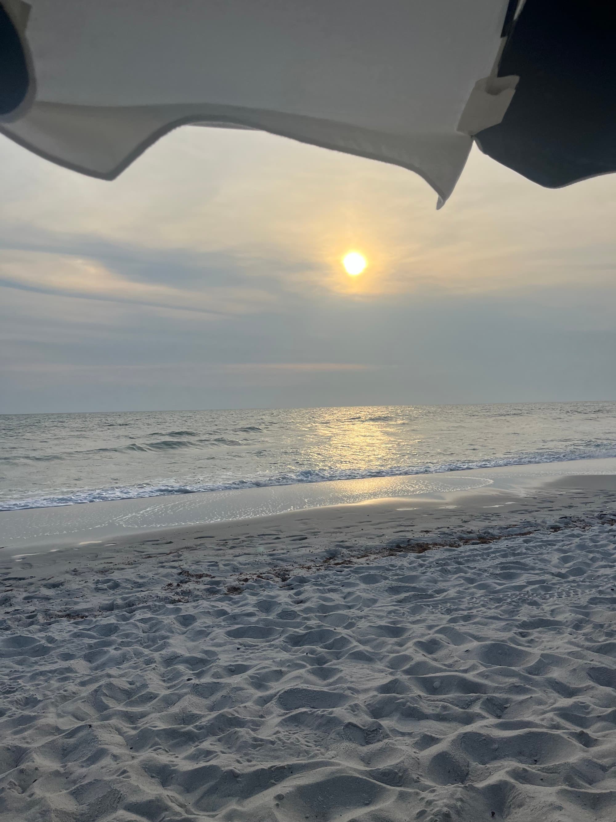 Sunset at the beach under an umbrella.