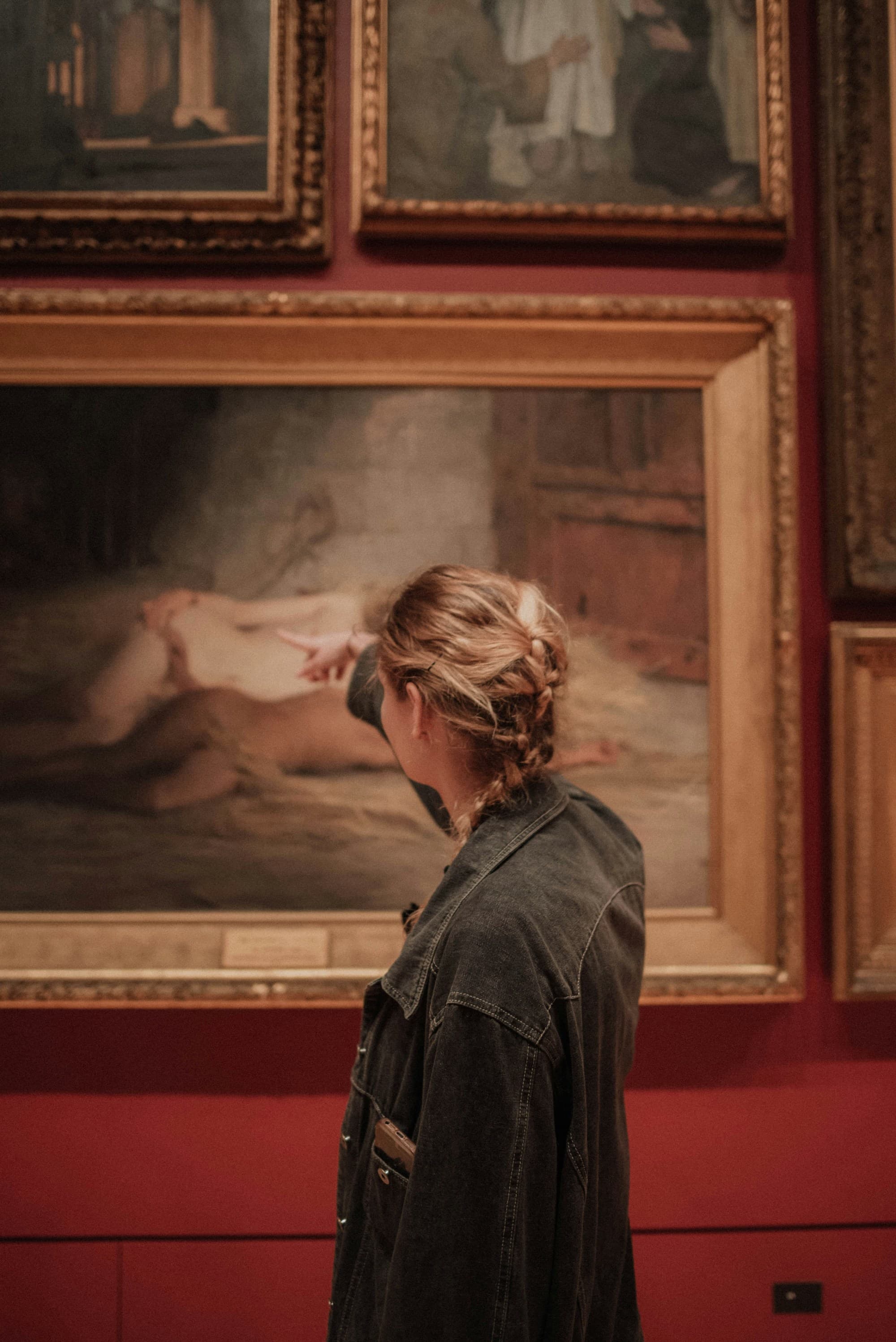 A person observing a painting in an art gallery, highlighting art appreciation and interaction.