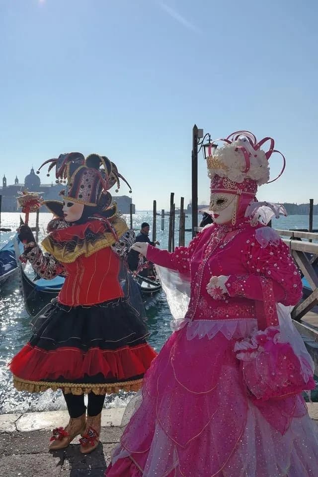 Two people in elaborate colorful costumes with masks.