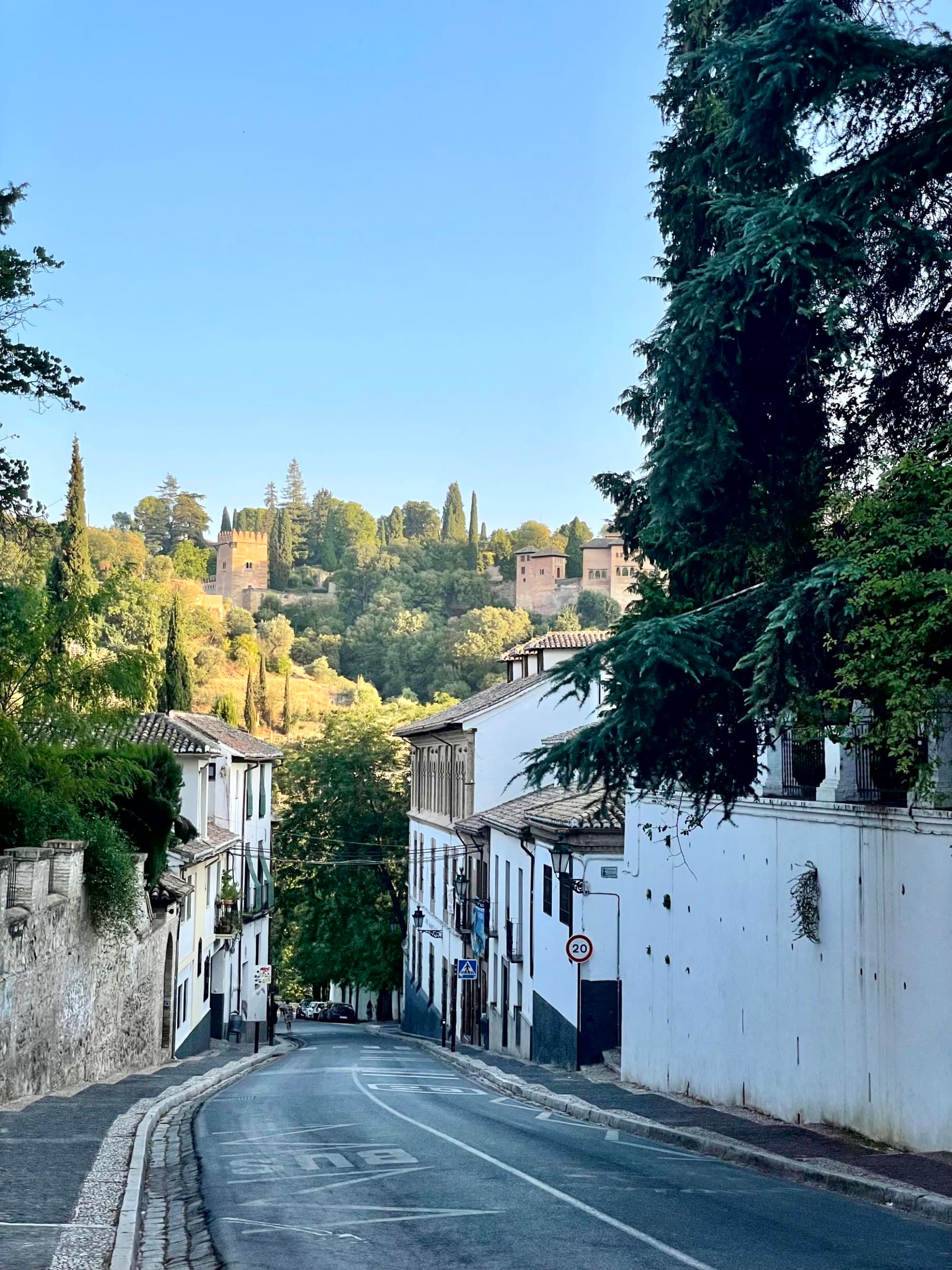 A serene street view with traditional white buildings under a clear blue sky, possibly in a historic European town.