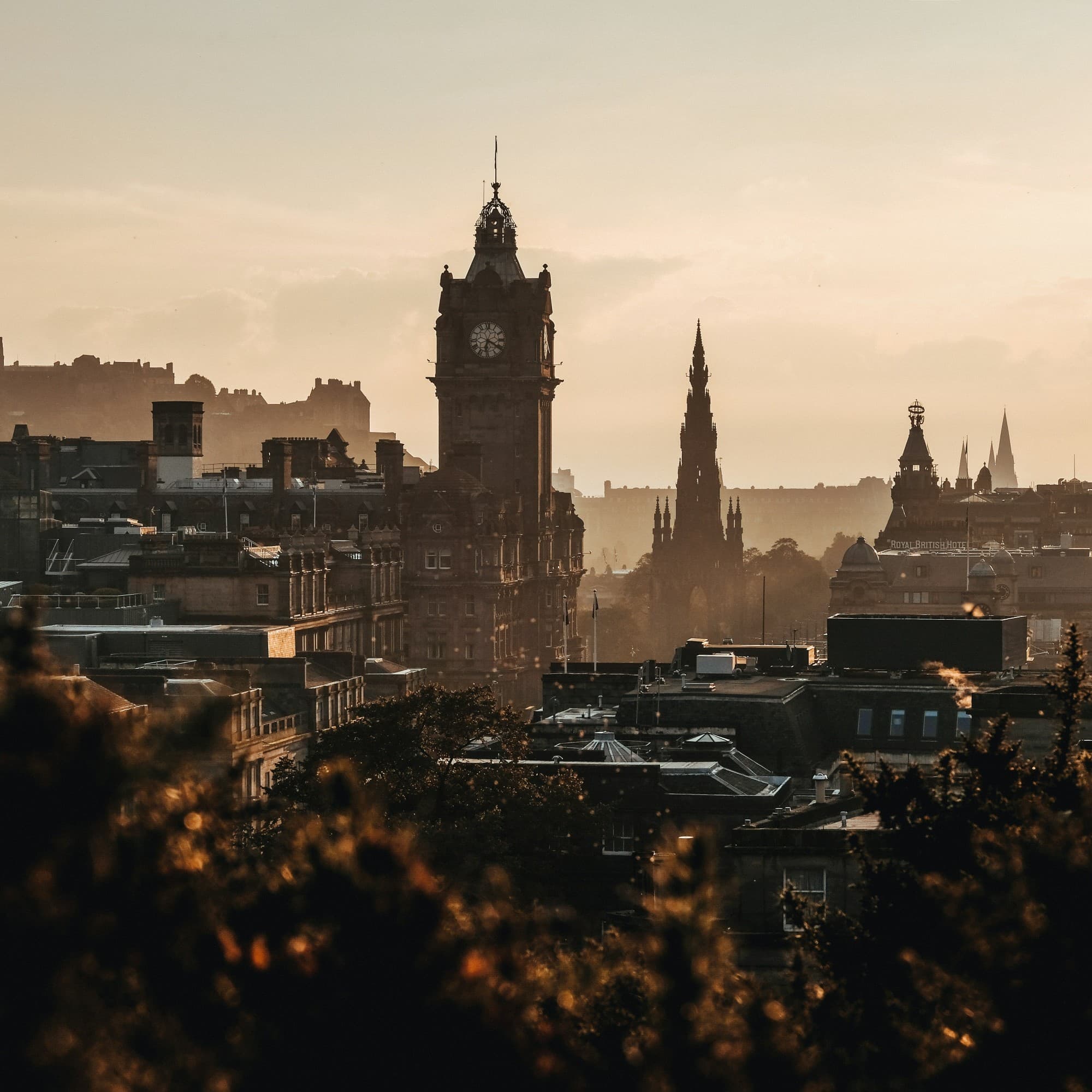 The image depicts a cityscape at sunset with historical buildings all bathed in warm light.