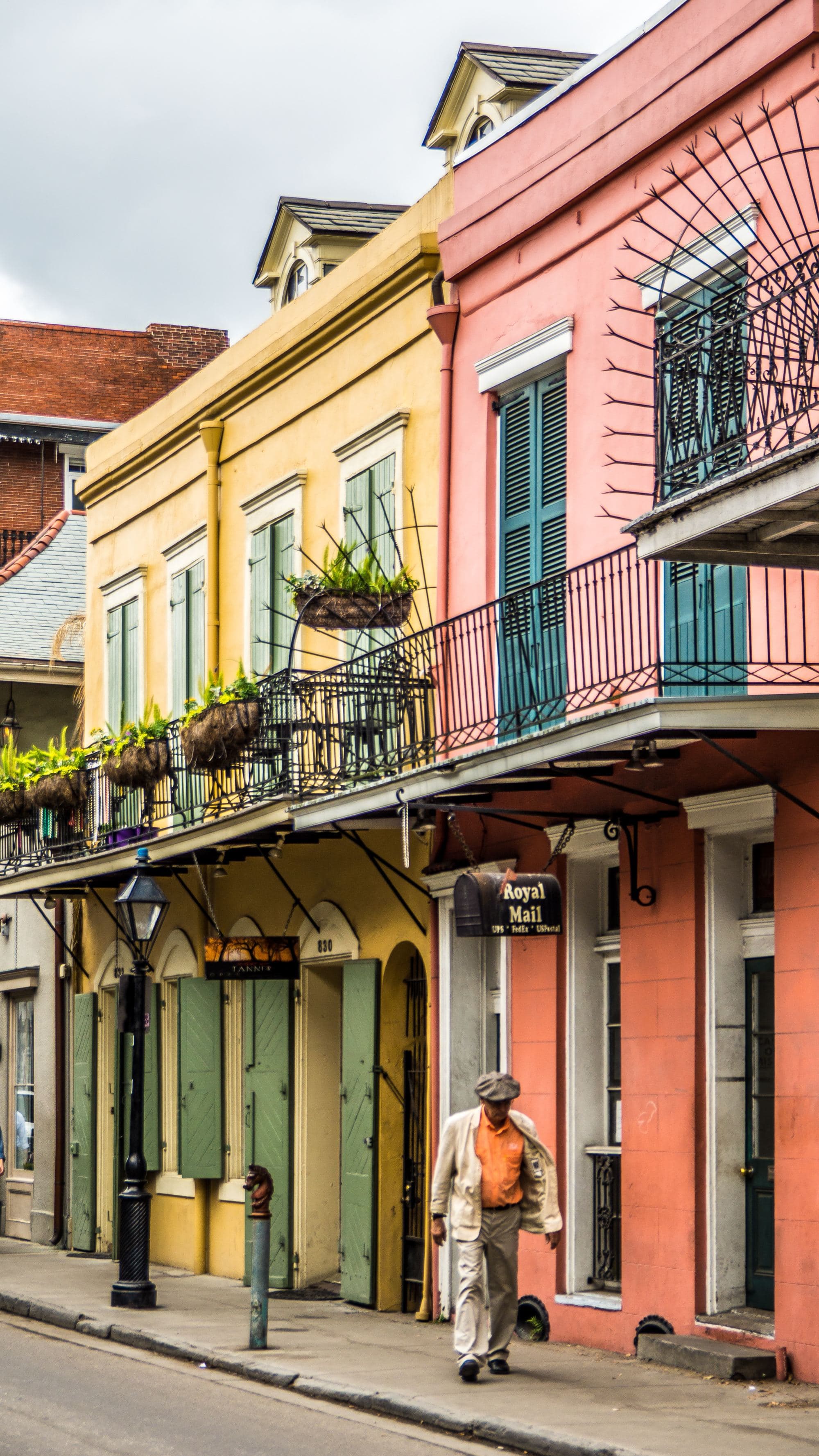 A man walking near colorful buildings on a street.