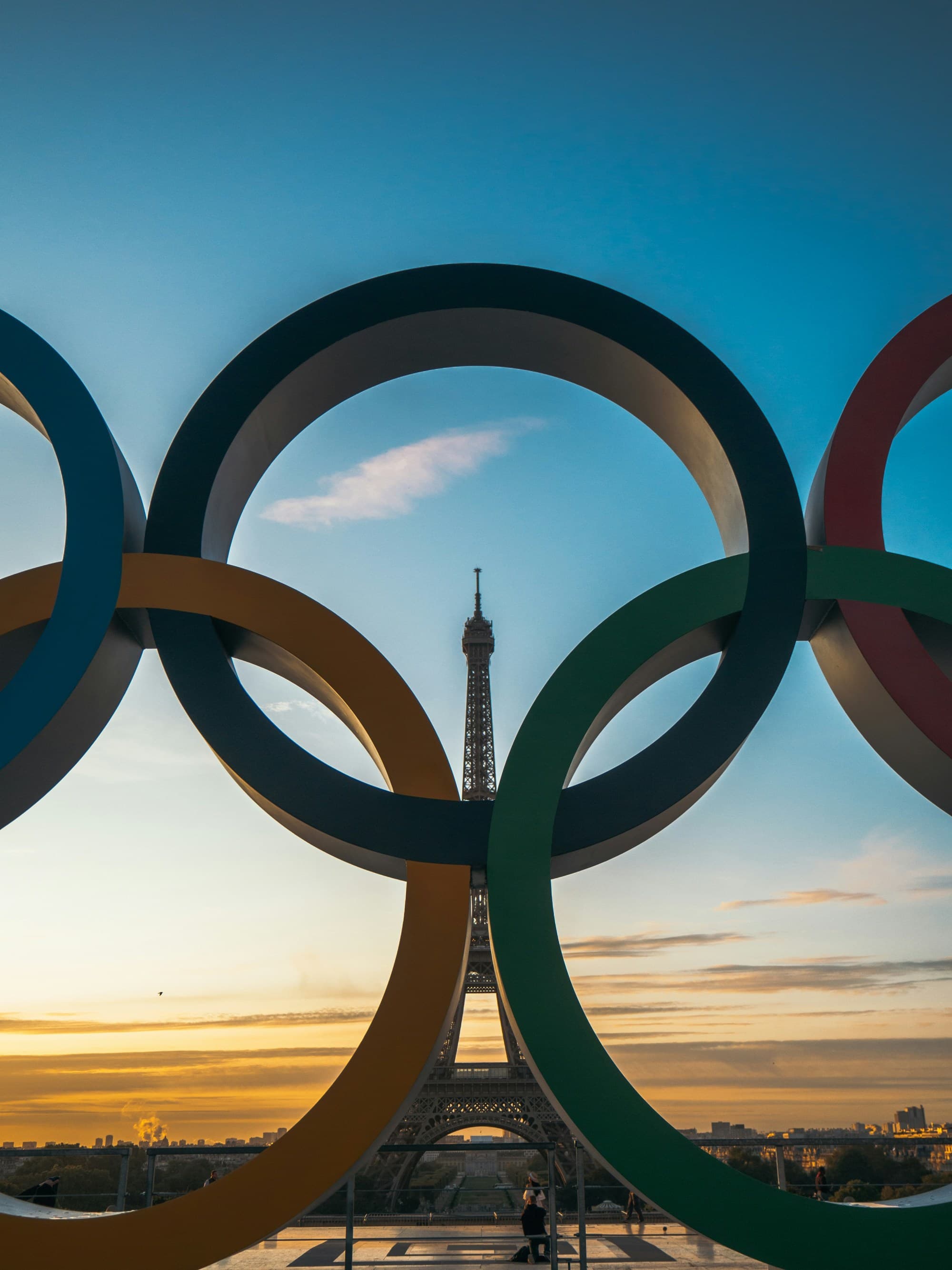 A low angled shot of the Olympics rings in front of the Eiffel Tower.