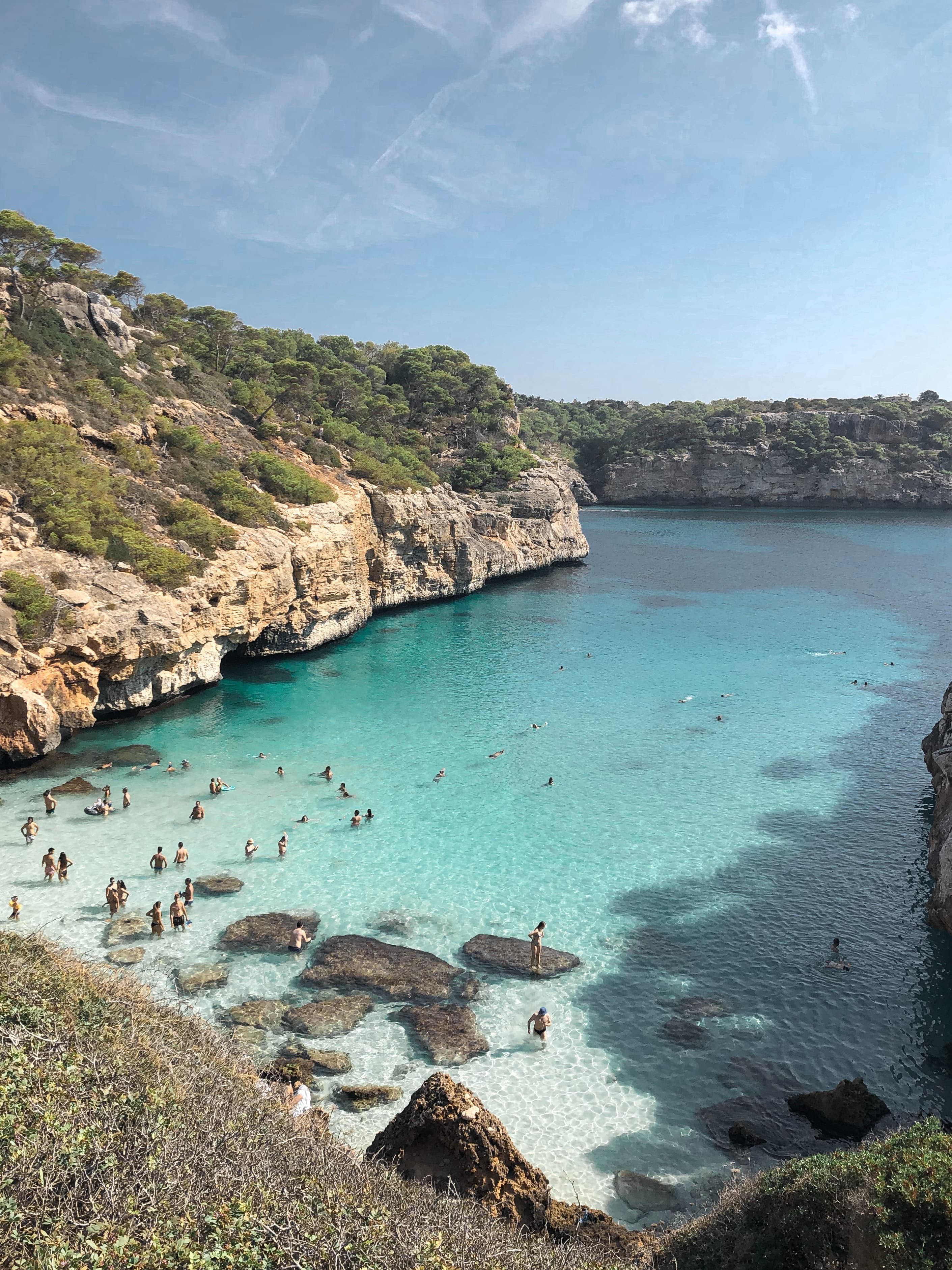 people swimming in turquoise waters surrounded by cliffs