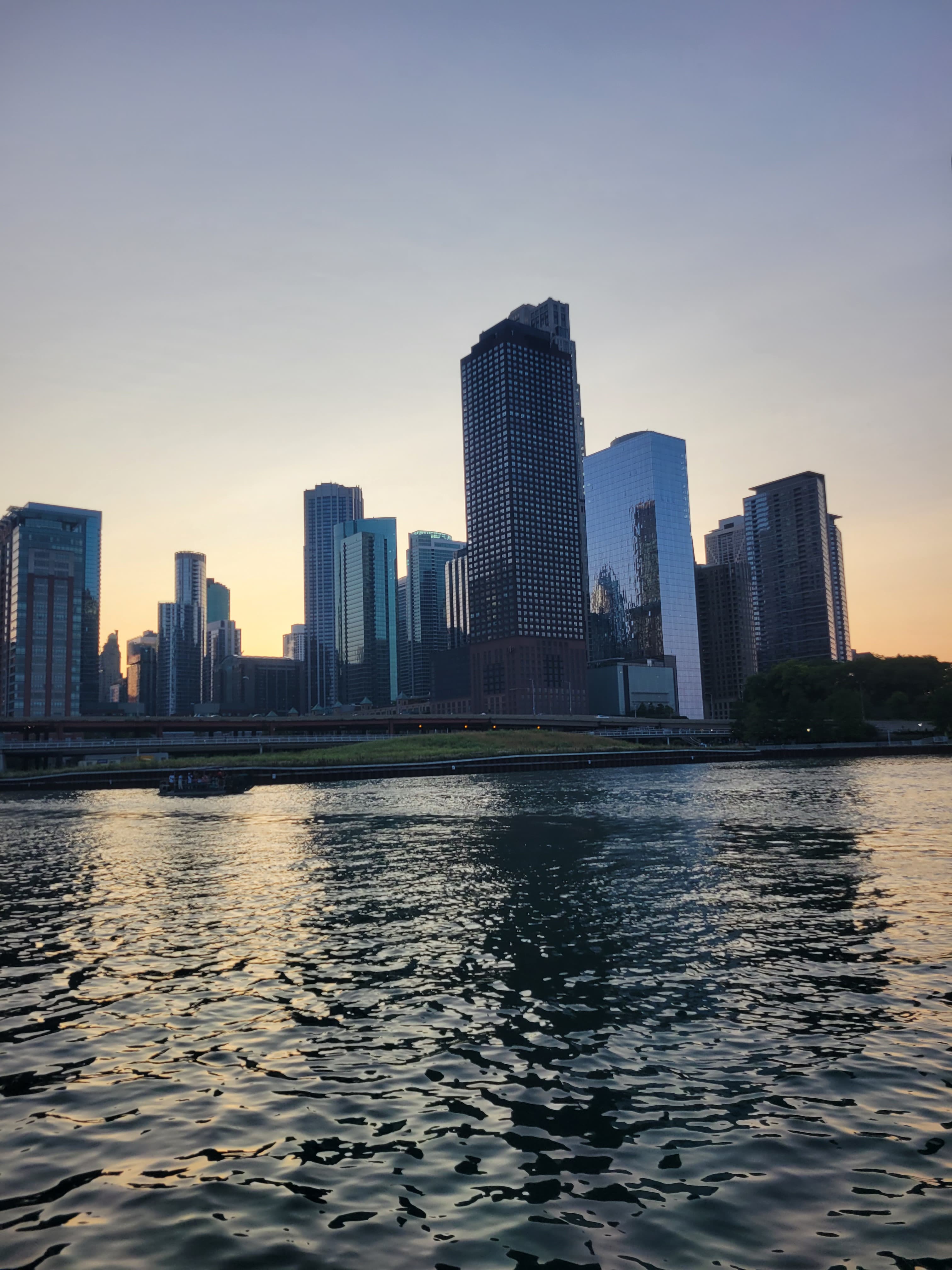 A photo of buildings behind a body of water in the evening.