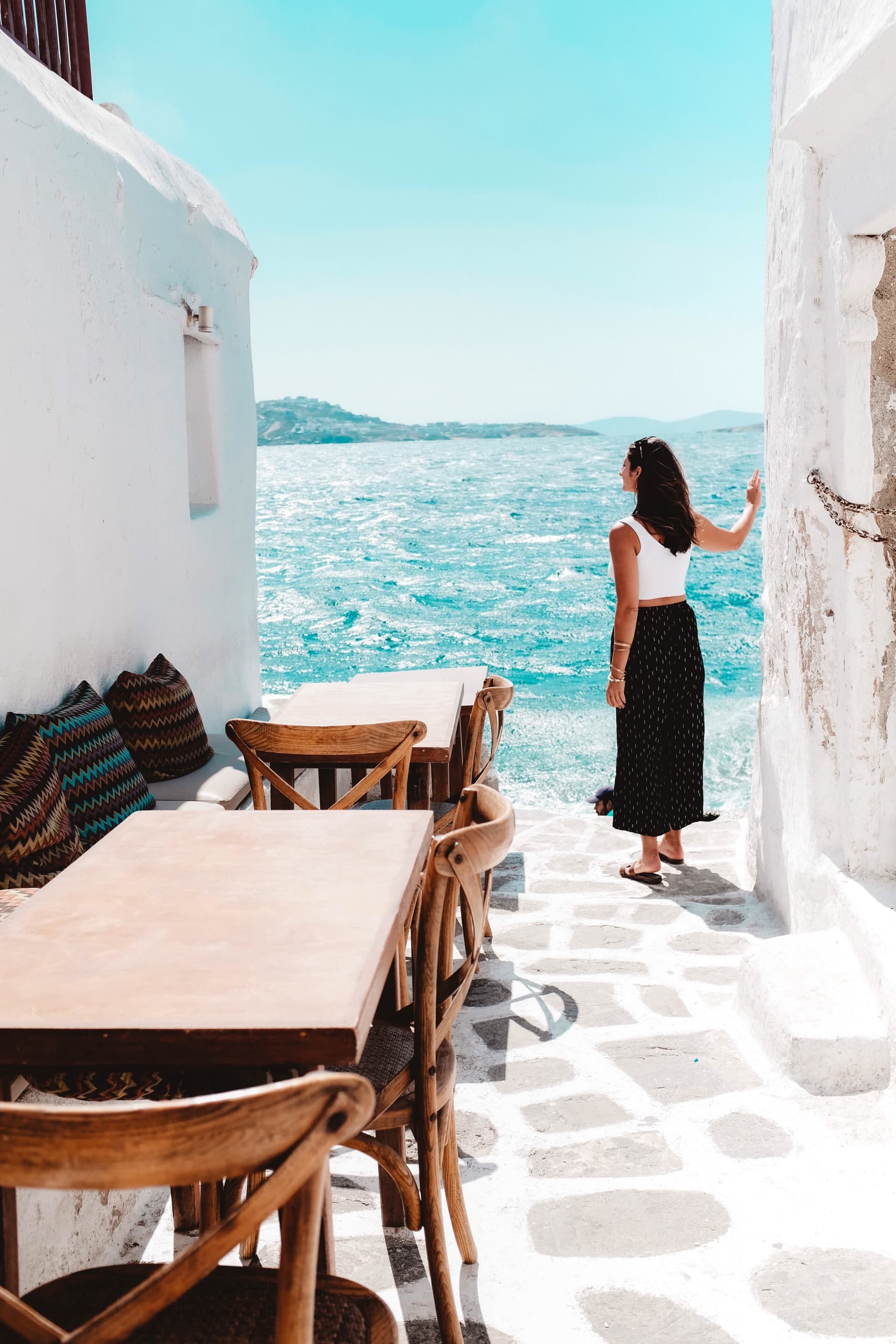 Woman wearing black skirt and white shirt standing next to white building and body of water during daytime