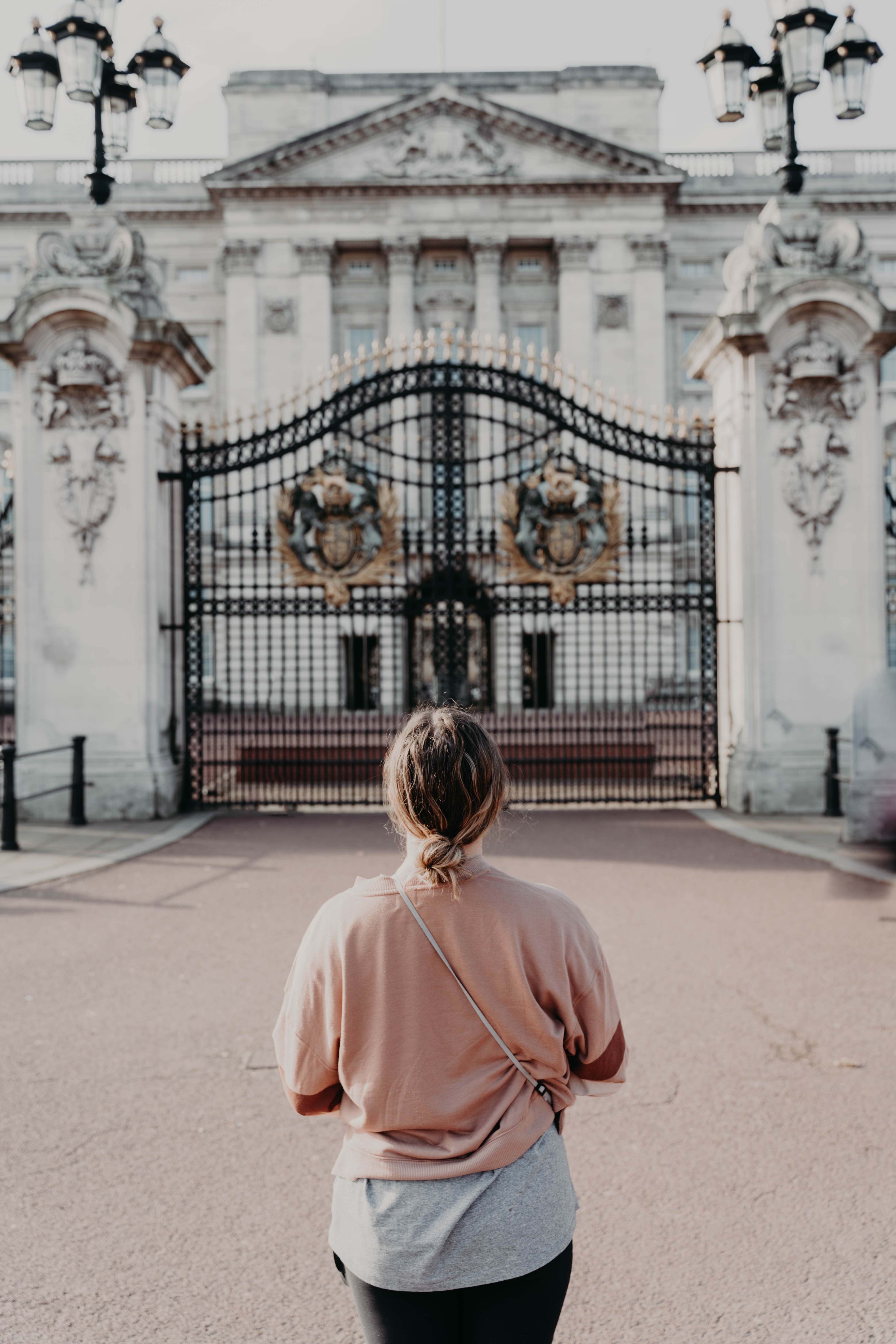 Person standing in front of large white building and black gates during daytime