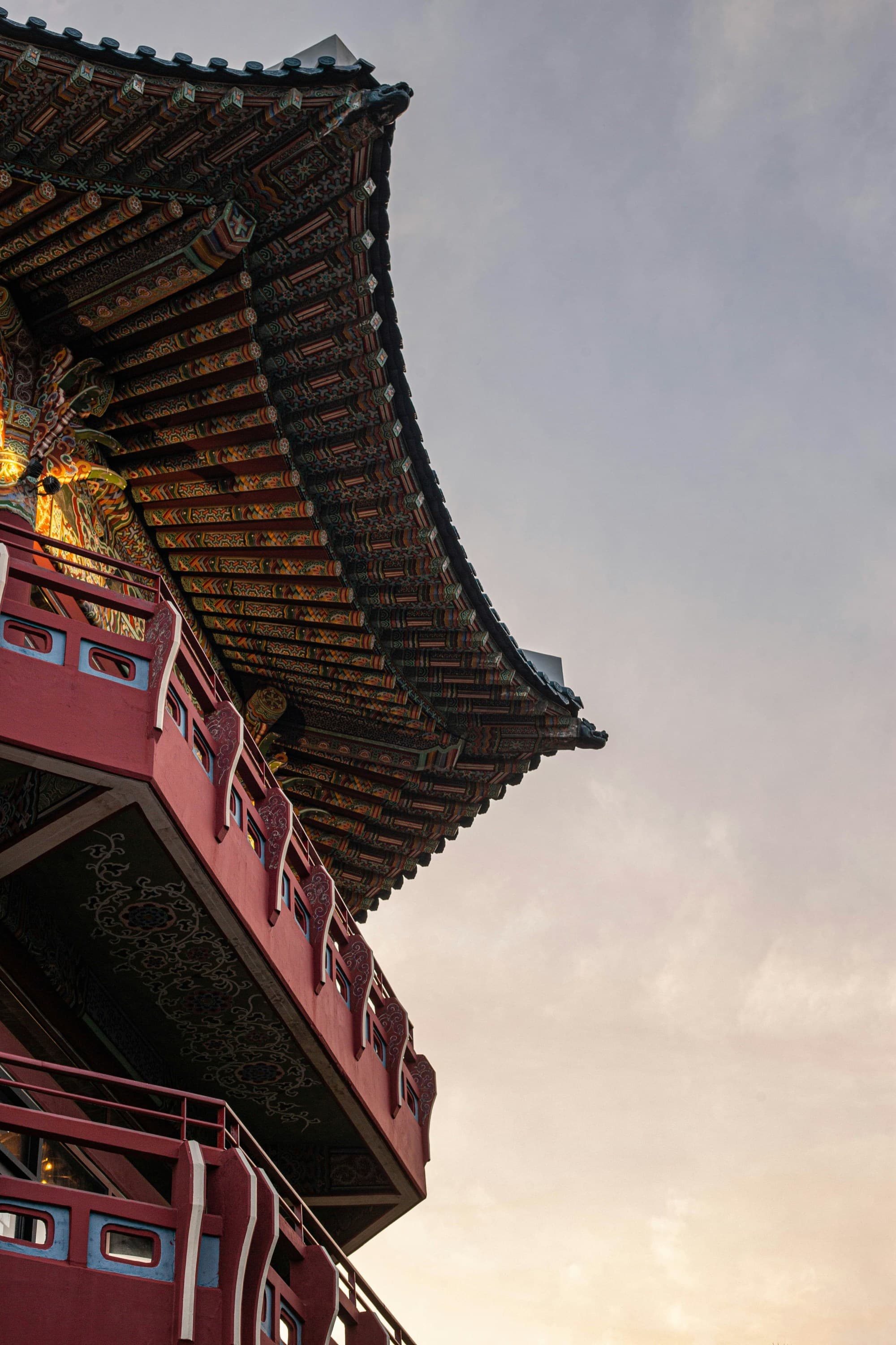 A low angled shot of a tall maroon building with golden roof taken during daytime.