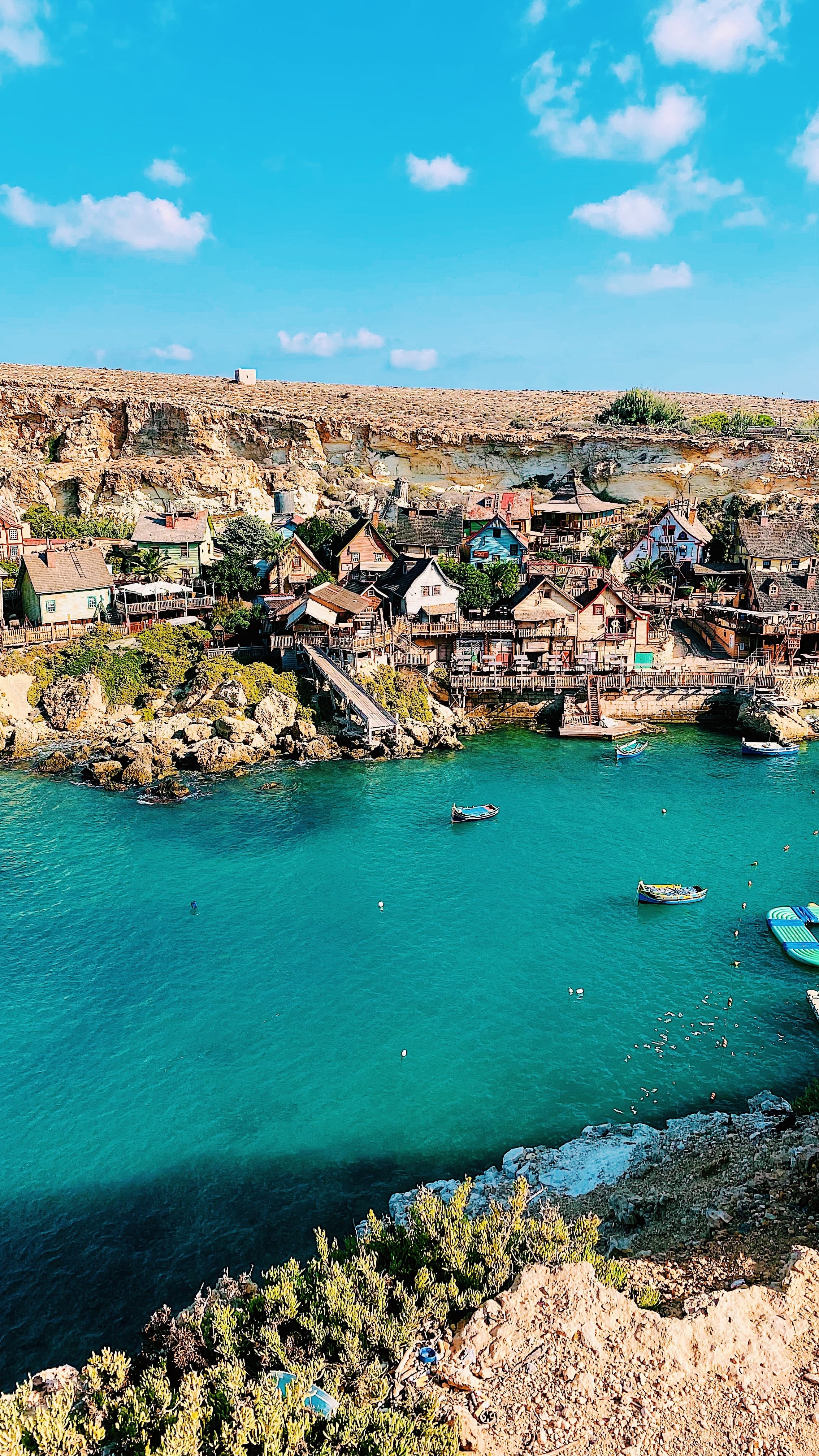 sailboats in a body of water next to a hill with houses during daytime