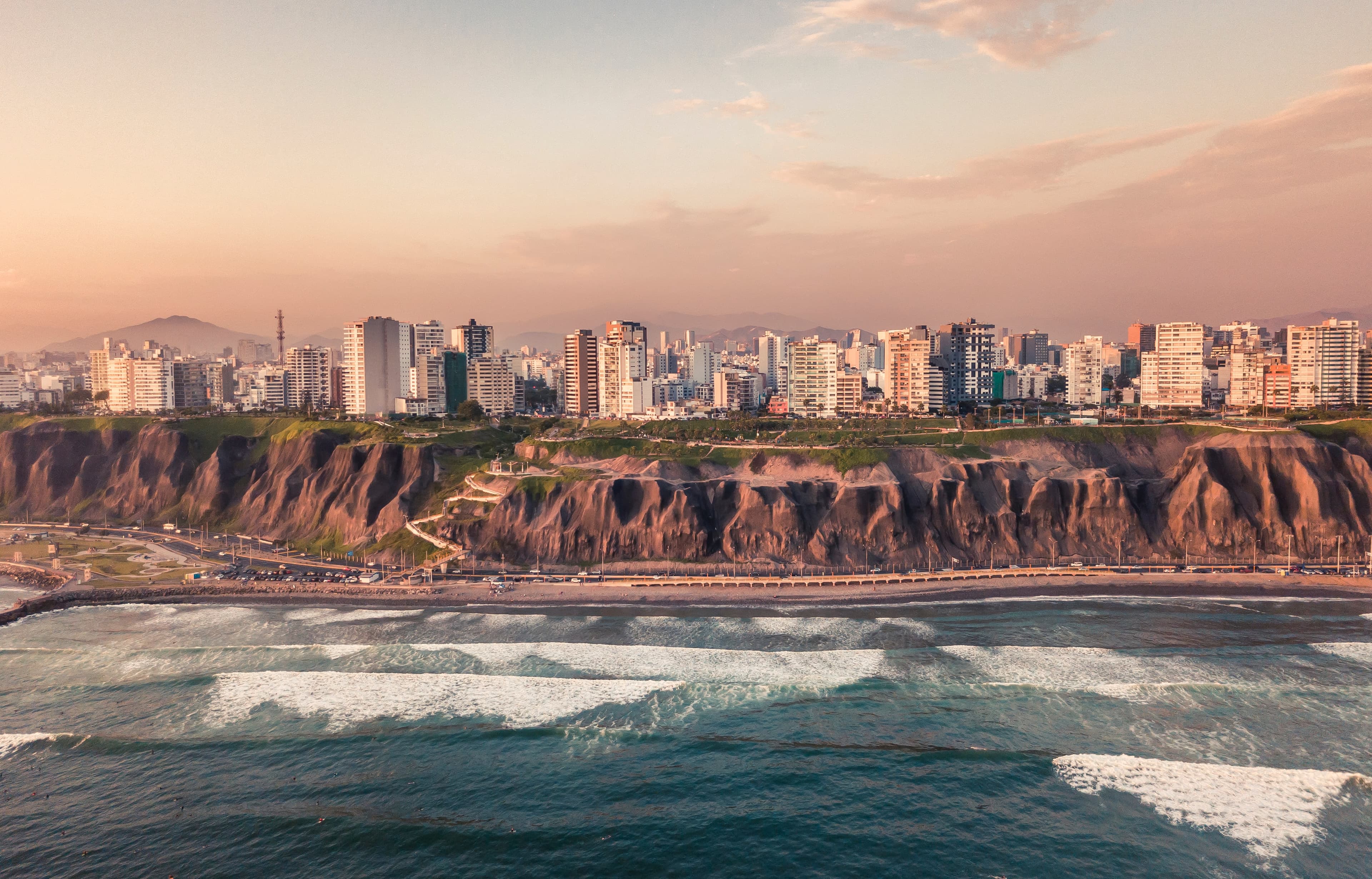 Lima, Peru city view over a cliff with ocean waves at sunset.