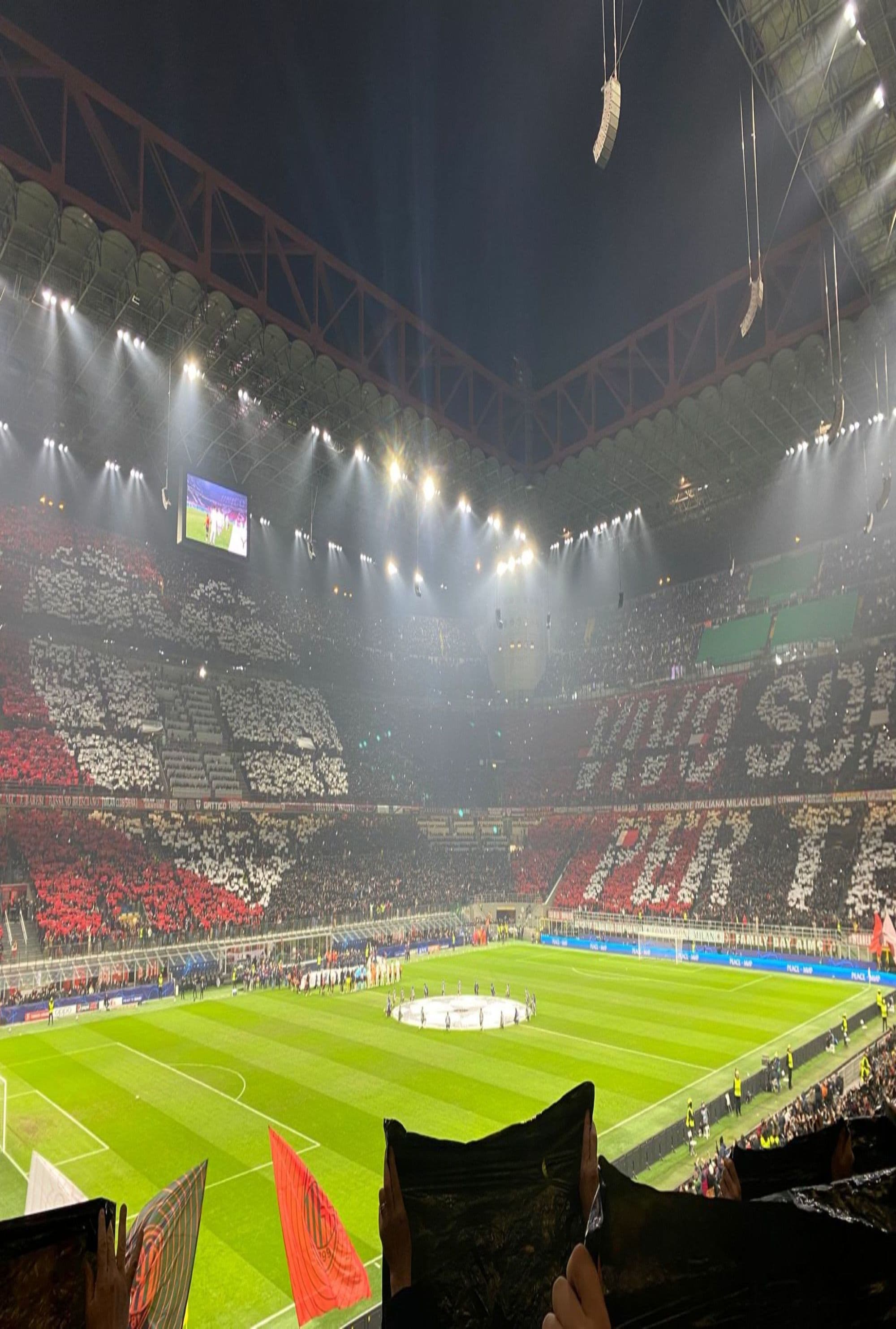 A stadium with people watching a sports game at nighttime.