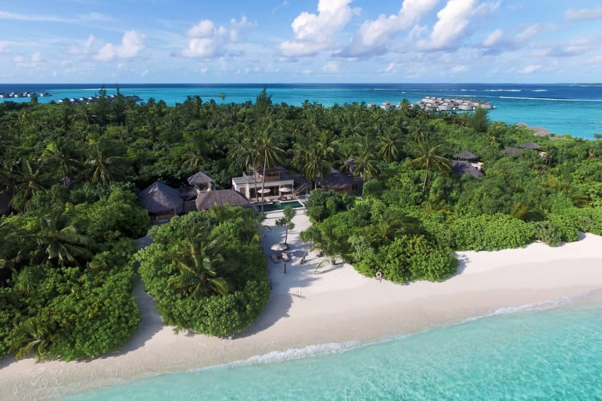 aerial view of villa on beach surrounded by trees during daytime