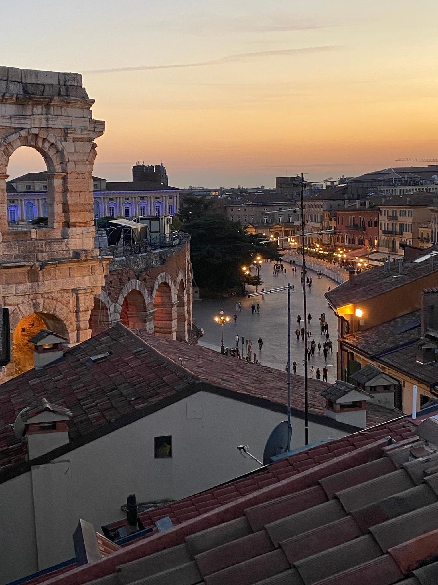 An aerial view of the city with tall tower in the middle of the city during sunset.