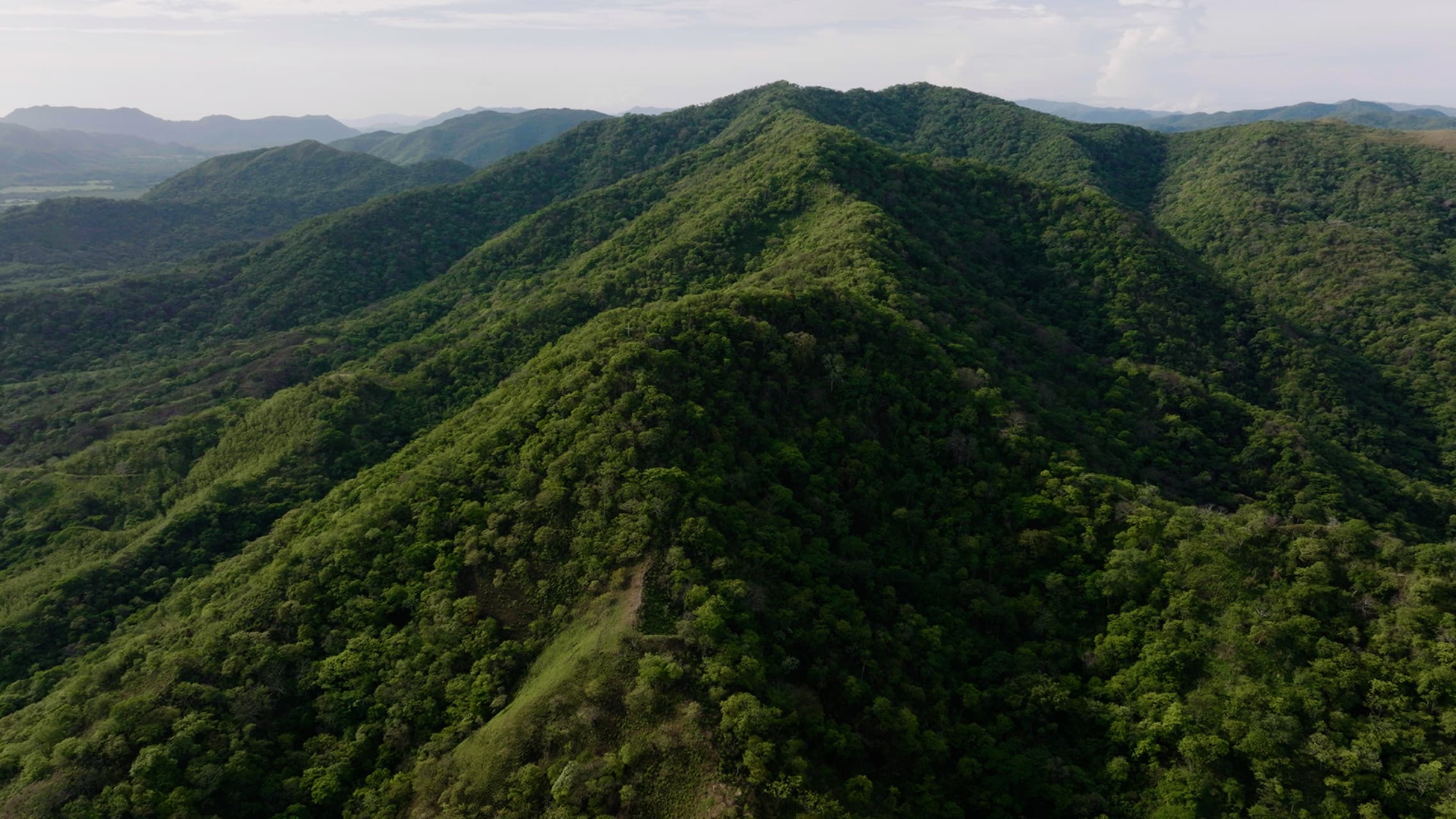 large green mountain with cloudy skies