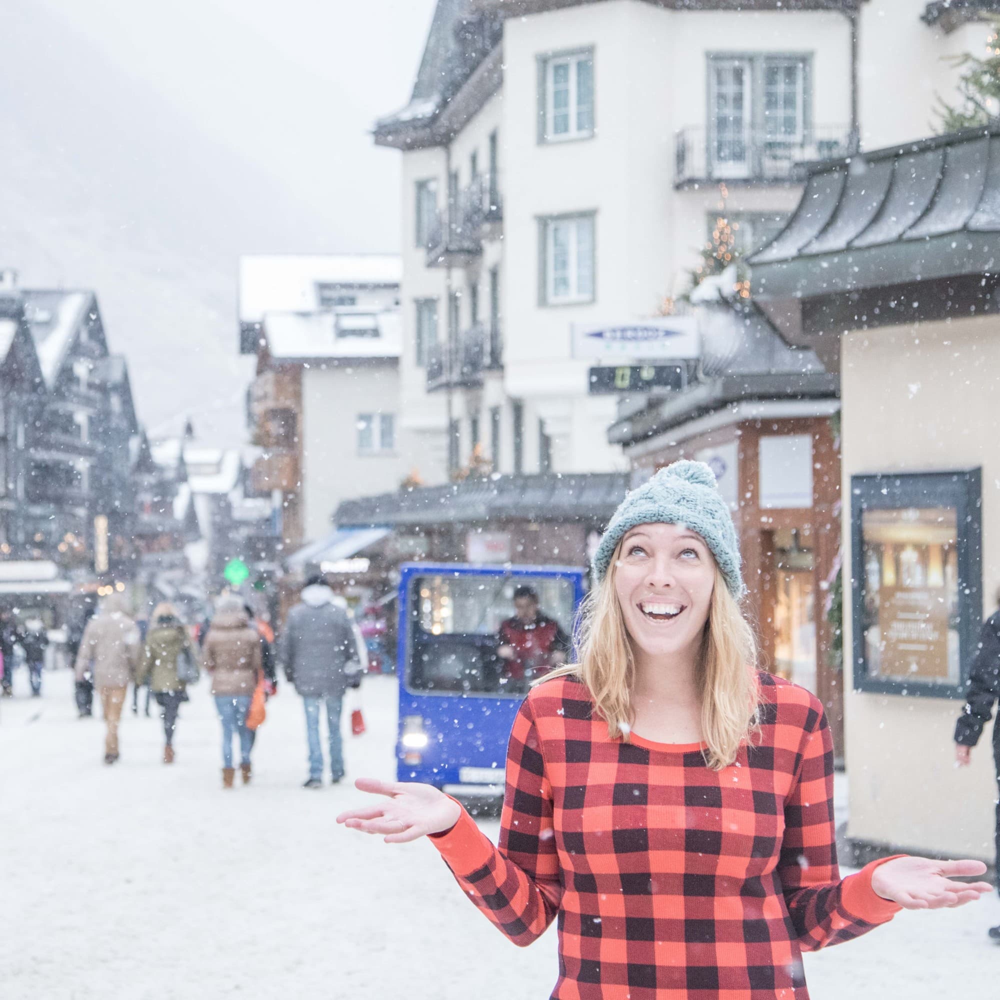 A woman enjoying snowfall in a red and black dress.