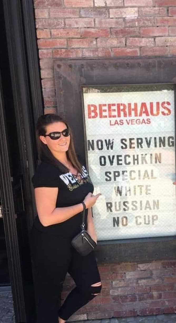 A woman in black t shirt posing with a board saying Beerhaus Las Vegas.