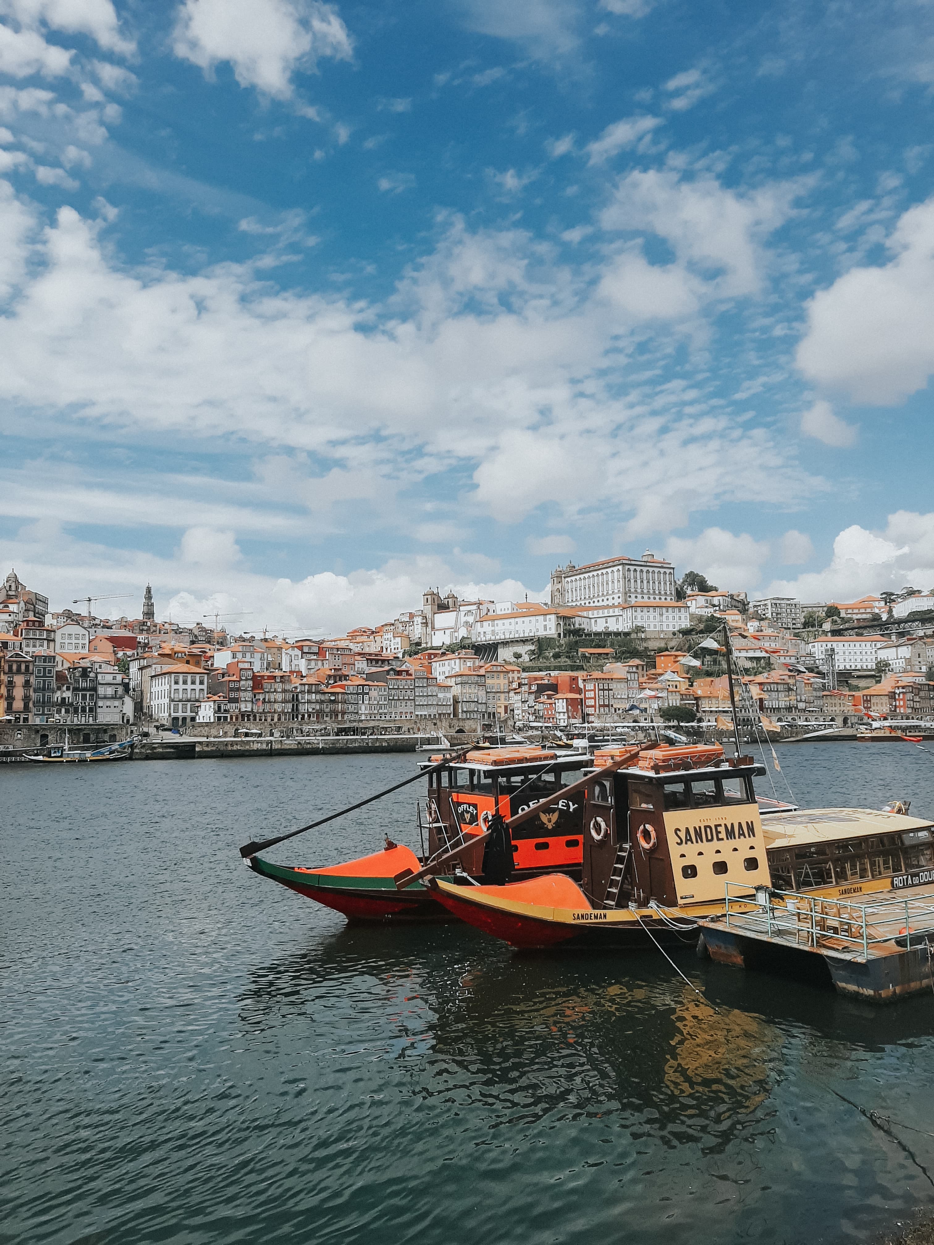 A scenic shot of the city from one side of the sea. Boat floating on the sea and city on the other side