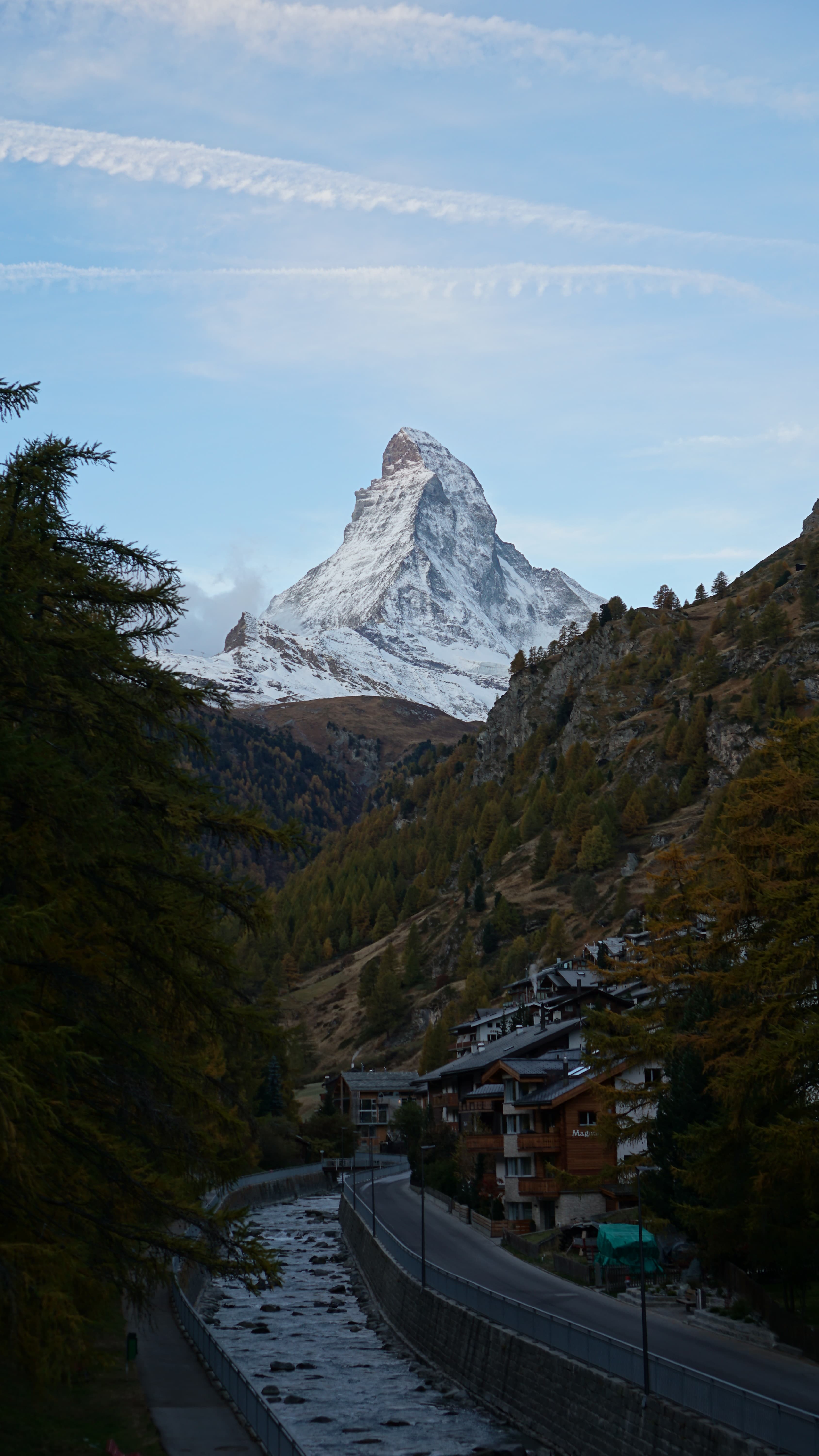 Large wooden mountain ski lodge in front of snowy alps in Switzerland.