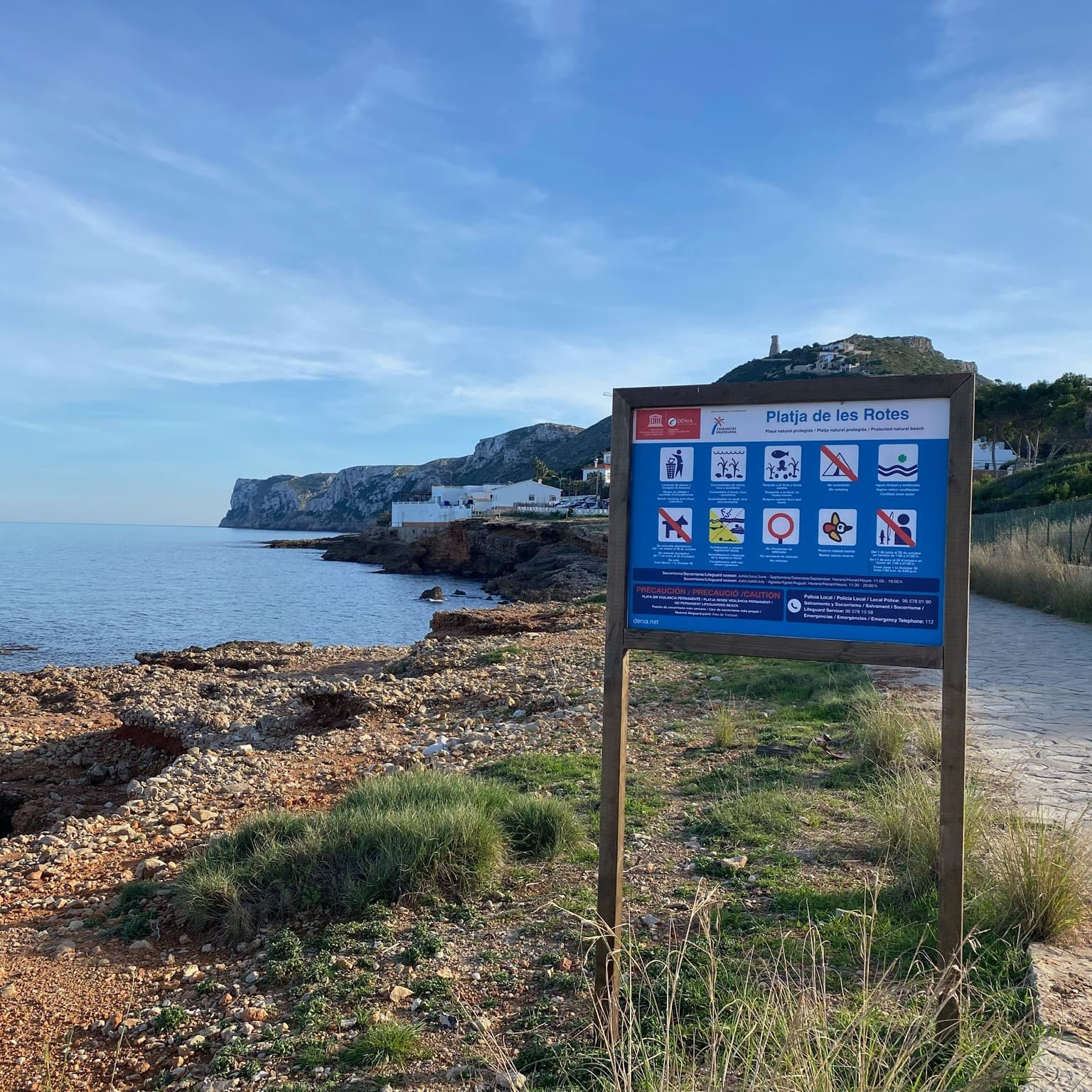 A blue board with coast at the back on a sunny day.