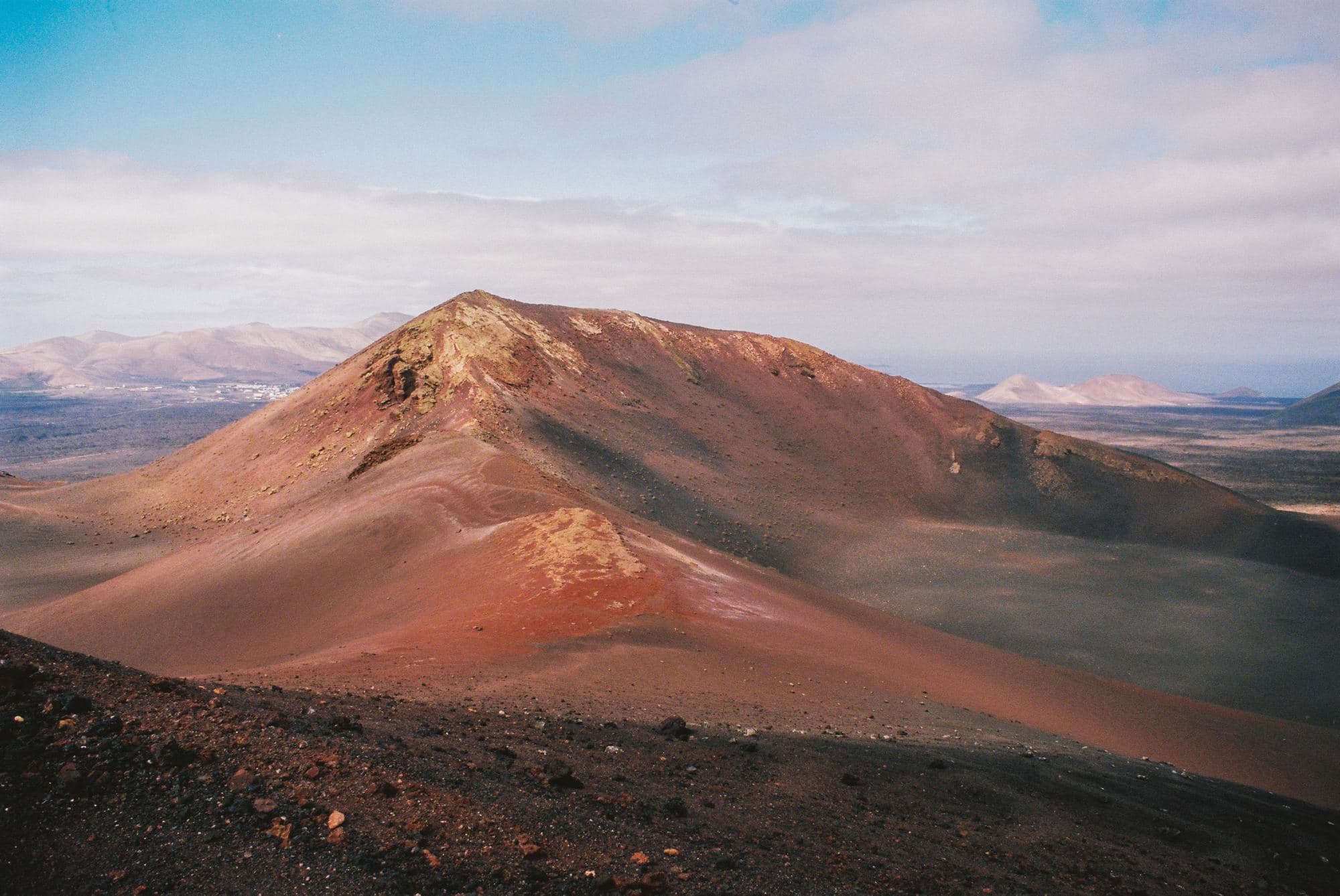 dessert sand dunes and volcano with a sunset on the horizon