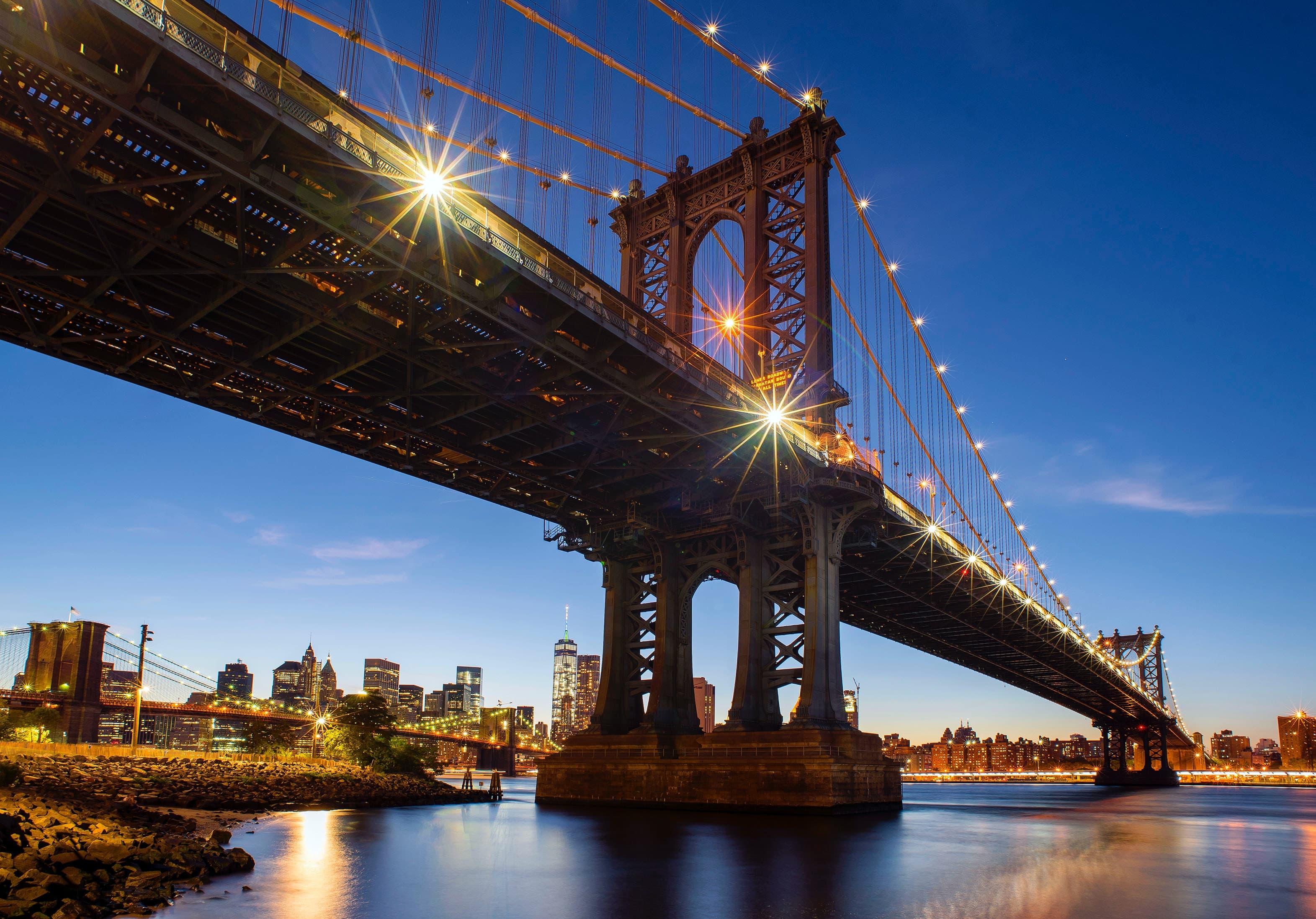 A bridge in NYC lighting with yellow lights at night.